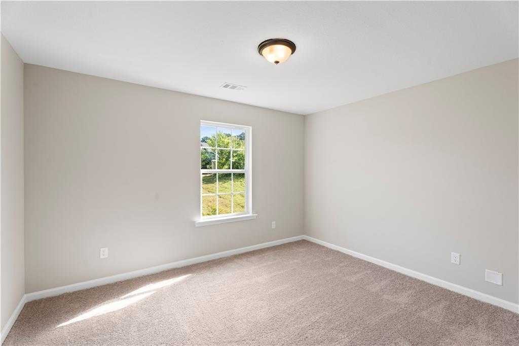 Bright secondary bedroom with neutral gray walls, carpeted flooring, and large window overlooking lush yard in Davidson Homes The Washington, Phenix City