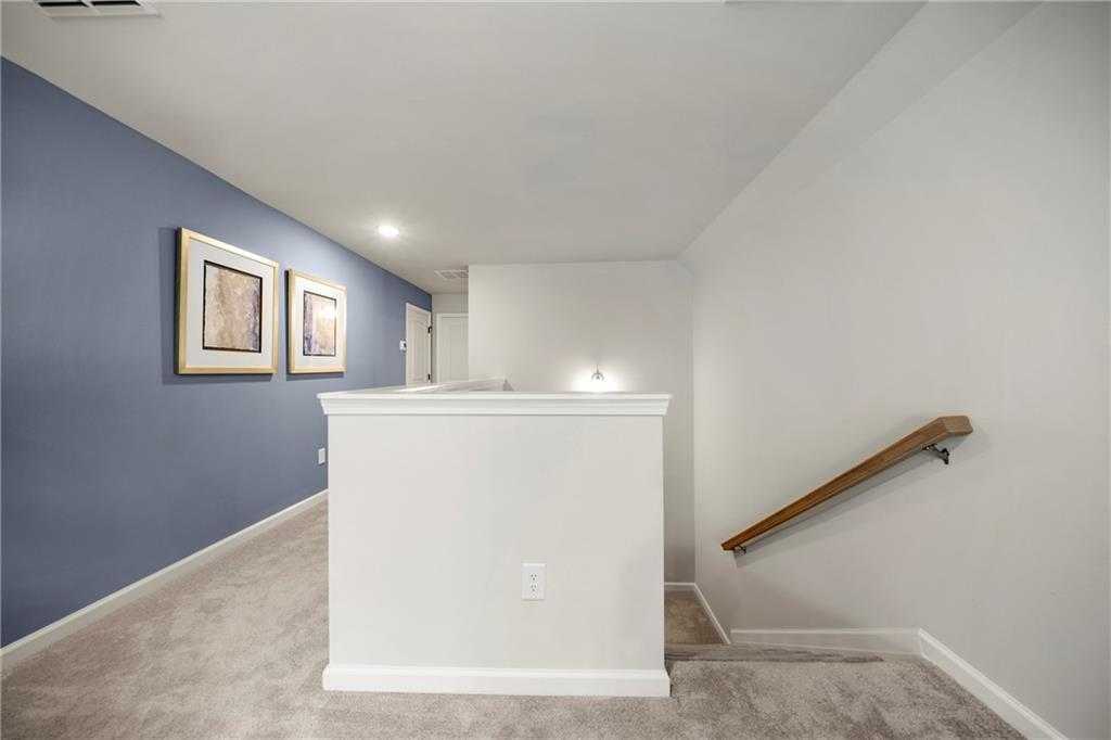 Upper hallway with blue accent wall, framed artwork, and wooden staircase railing in Davidson Homes The Hickory B, Dallas, Georgia