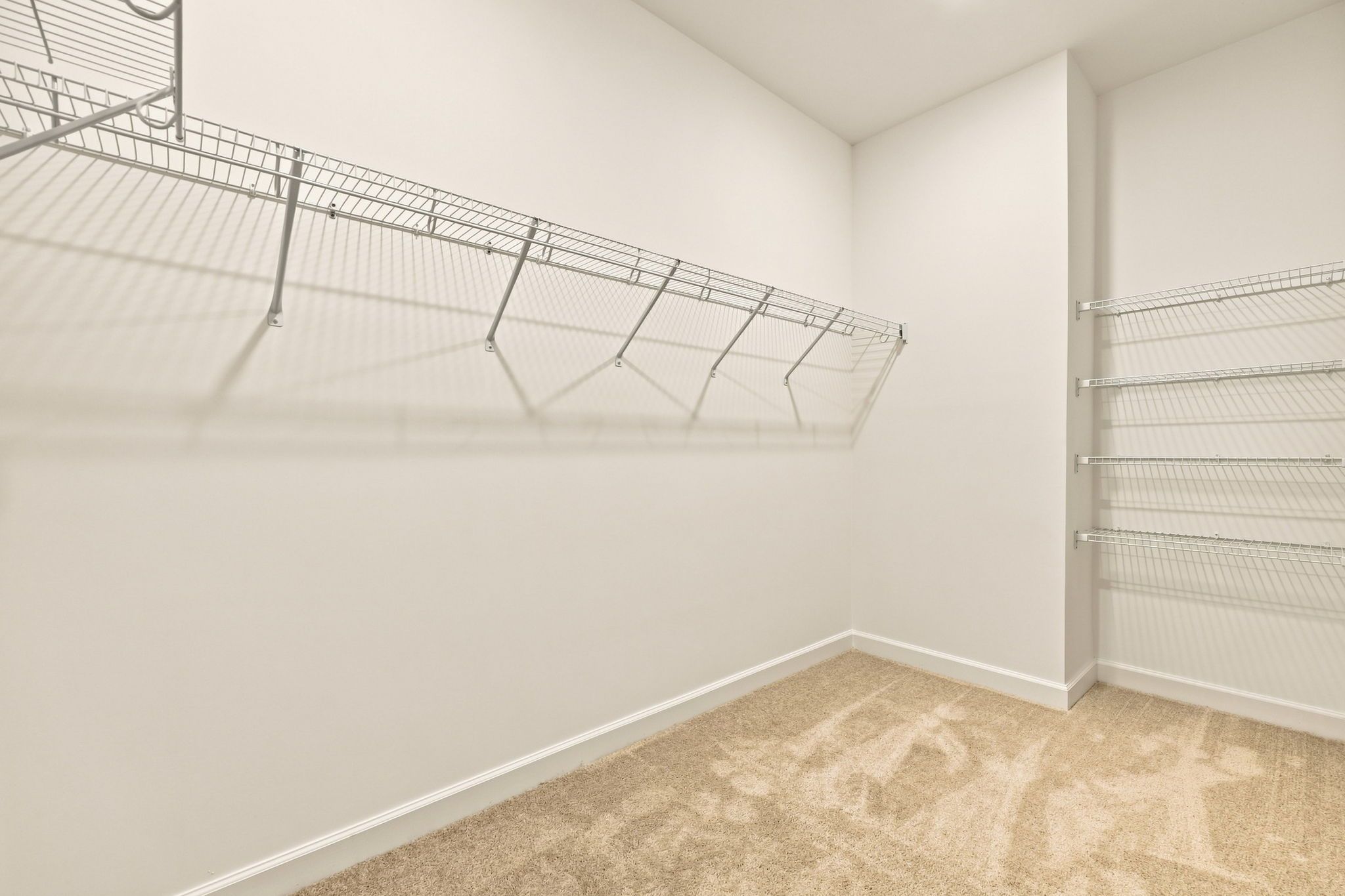 Spacious walk-in closet in The Jordan master suite with built-in wire shelving and plush carpeting.