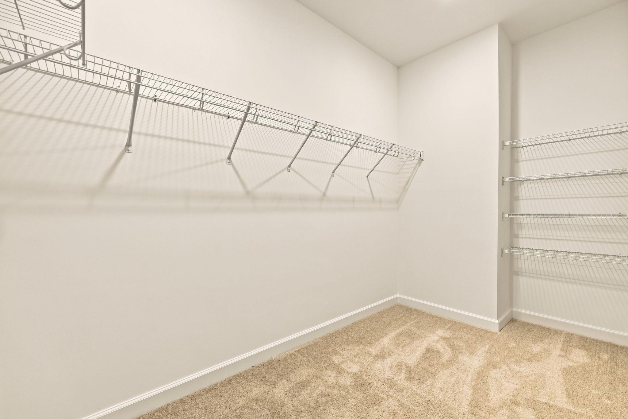 Spacious walk-in closet in The Jordan master suite with built-in wire shelving and plush carpeting.