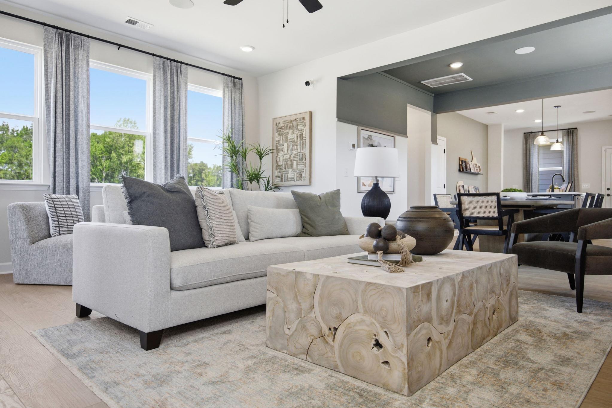 Open-concept living room in The Burke C home design featuring a modern light wood coffee table and neutral furniture.