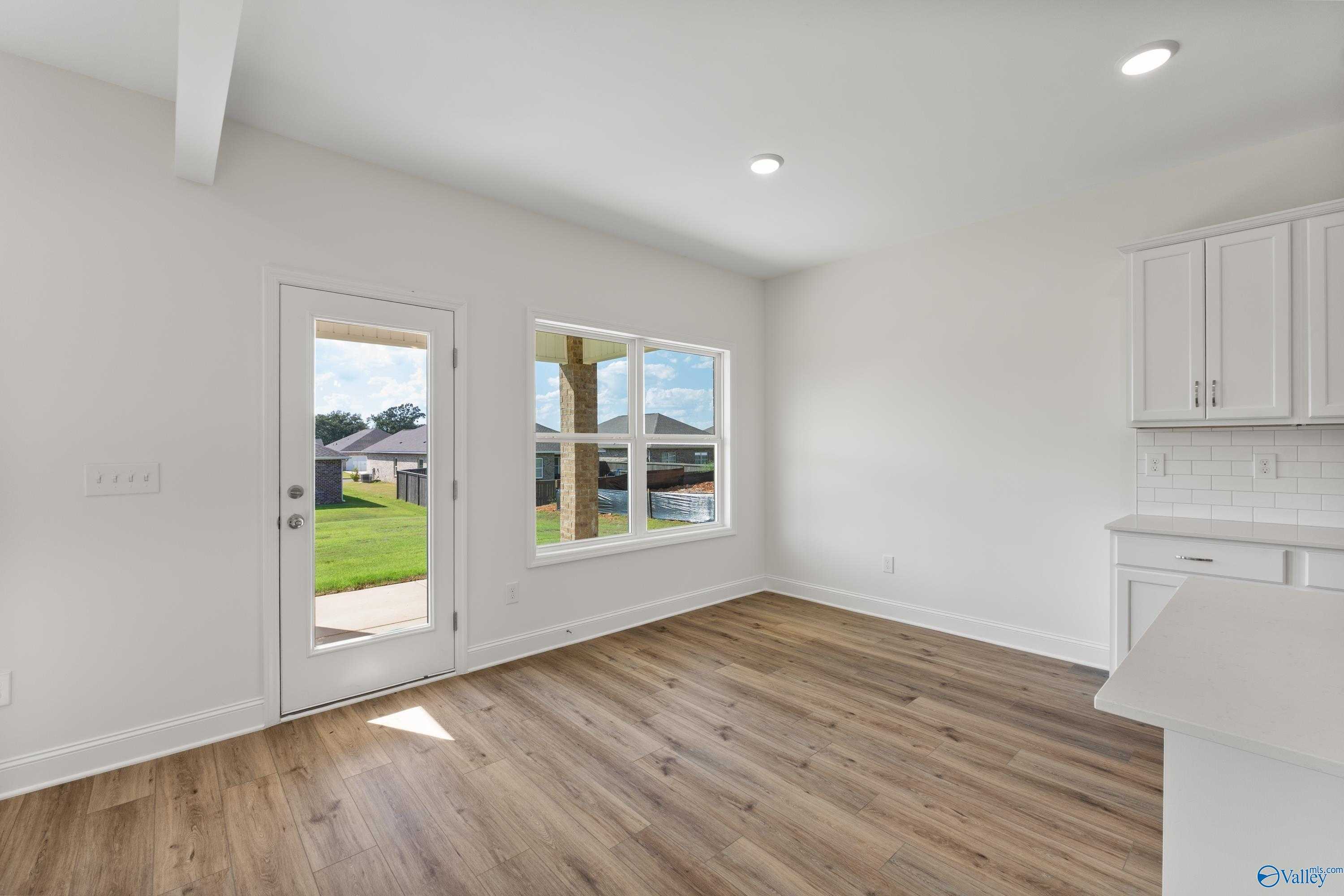 Bright breakfast nook with white cabinets, hardwood floors, and views of lush backyard in Davidson Homes The Shelby A, New Market, Alabama