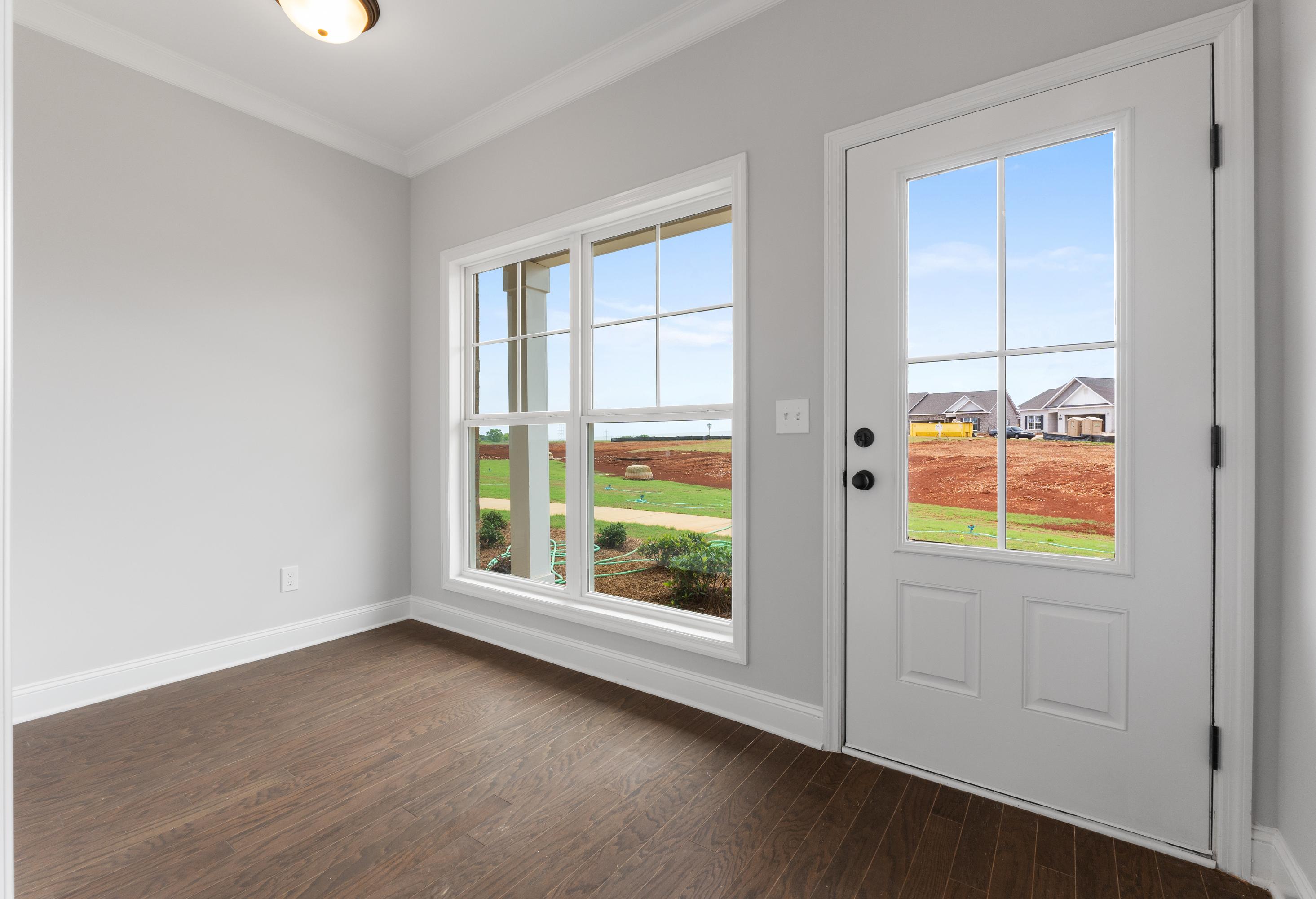 Bright interior room in The Copeland 2-bedroom home design featuring gray walls, hardwood floors, and glass door to backyard view