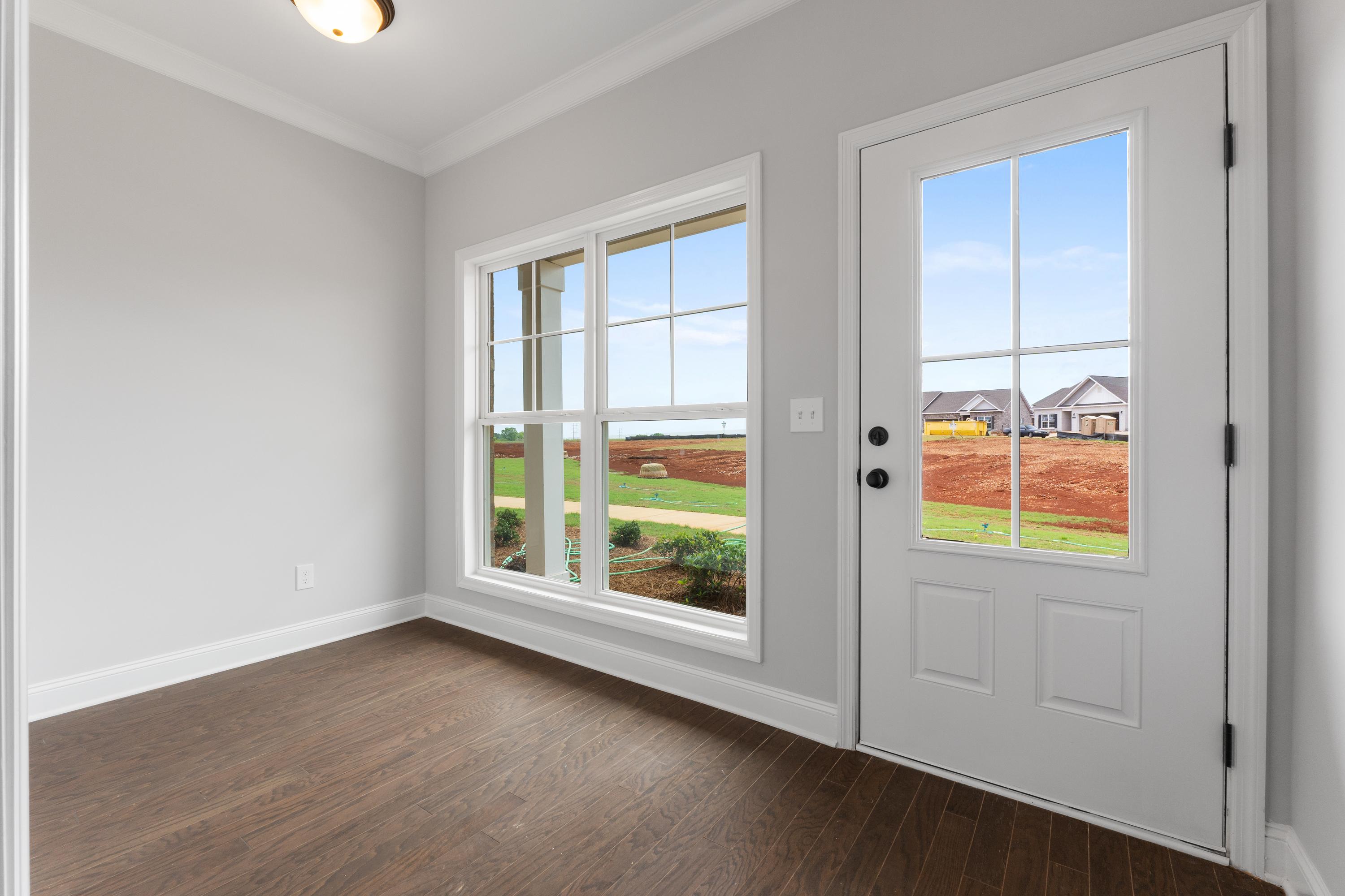 Bright interior room in The Copeland 2-bedroom home design featuring gray walls, hardwood floors, and glass door to backyard view