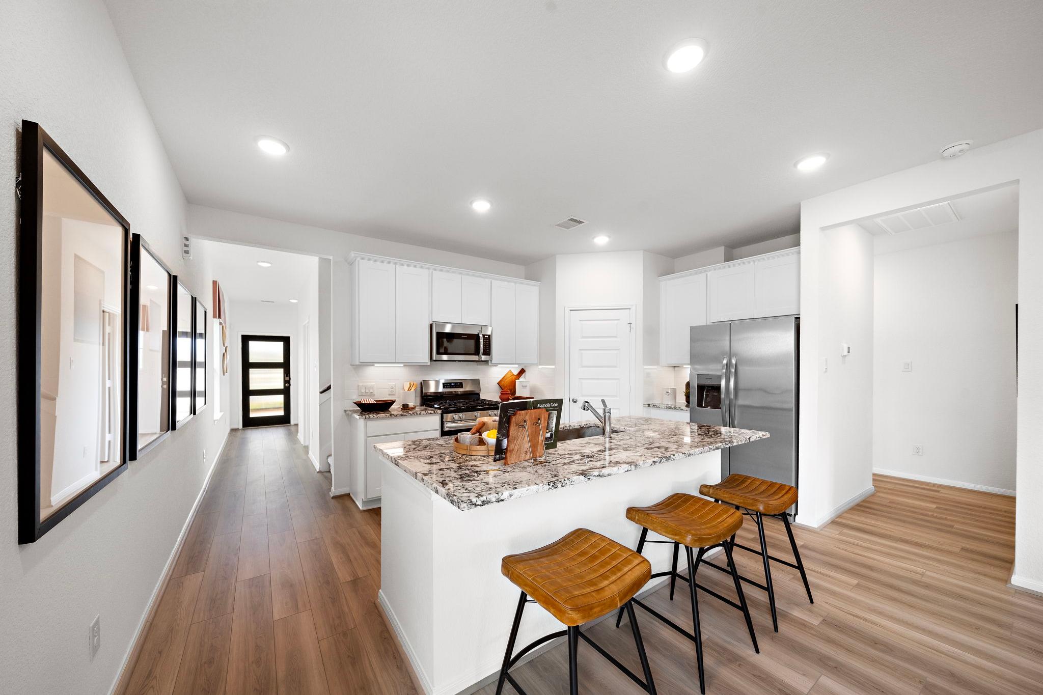 Spacious modern kitchen at The Villages at WestPointe in Dayton Texas with white cabinets granite island and hardwood floors