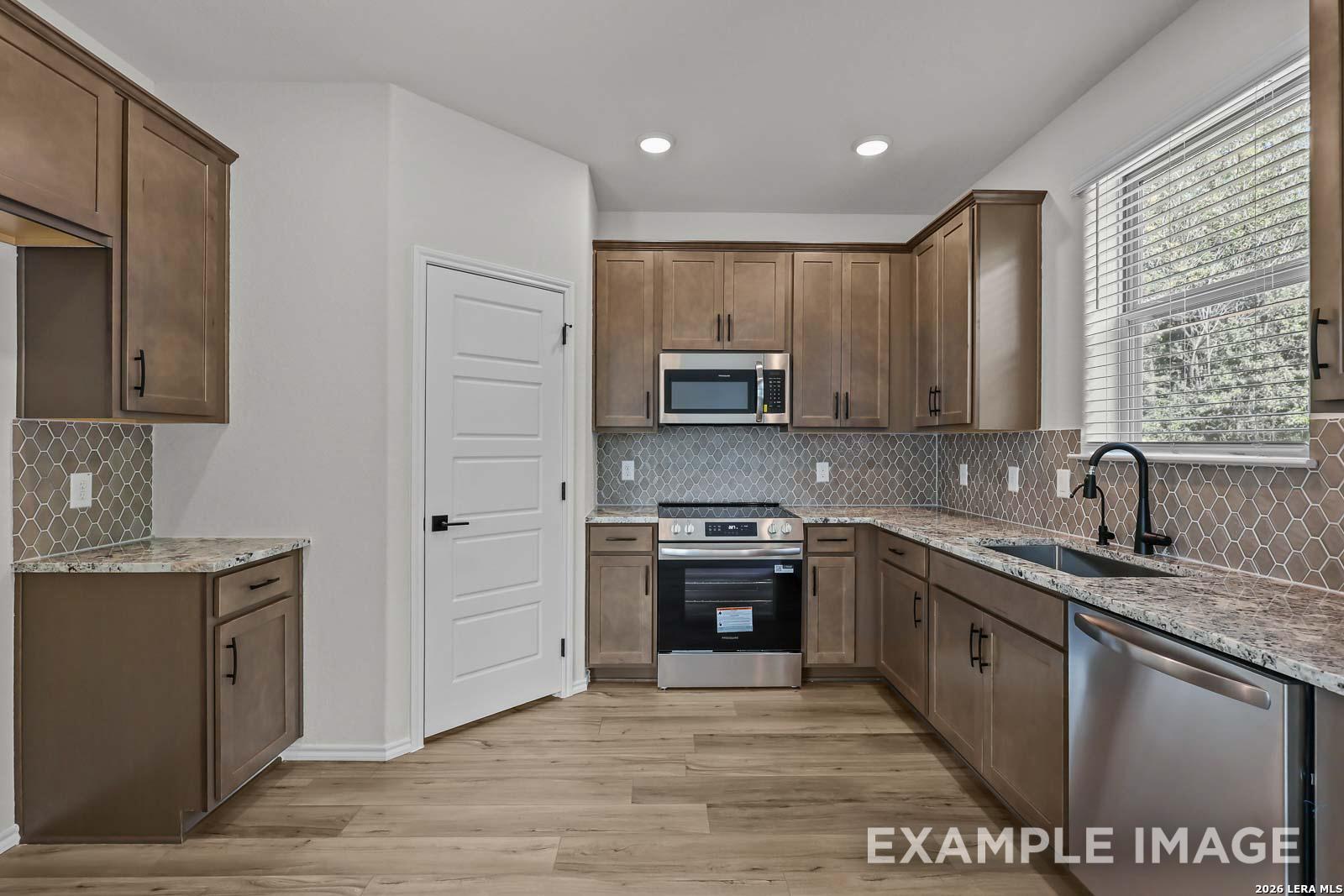 Modern kitchen with granite countertops, stainless appliances, and tile backsplash in Davidson Homes Florence D floor plan.