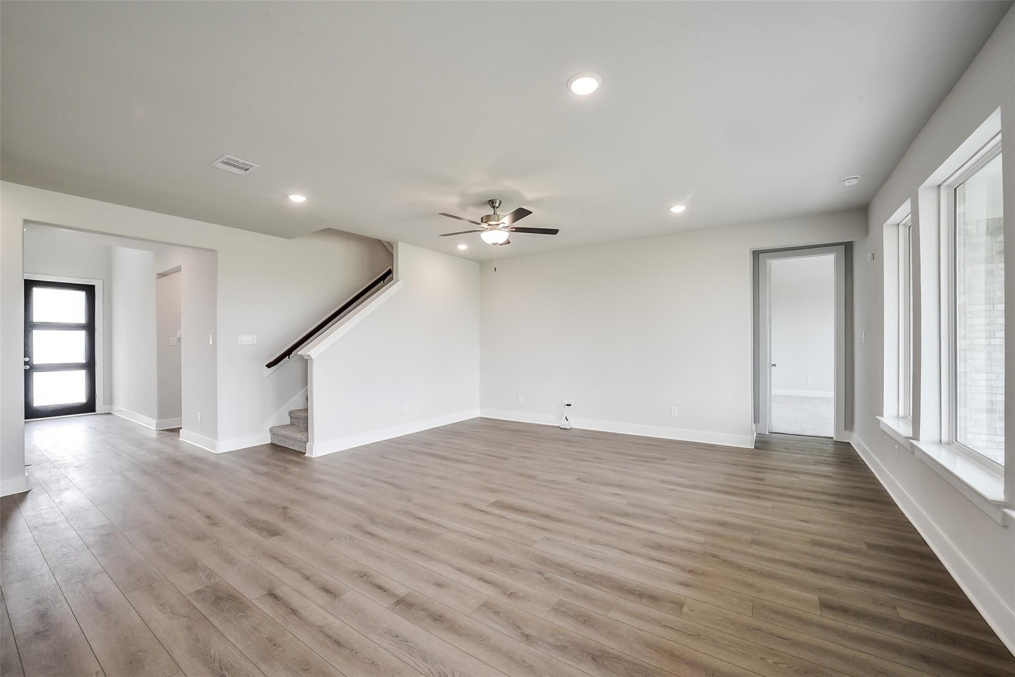 Spacious entry foyer with curved staircase, dual ceiling fans, and large windows in 4-bedroom Davidson Homes The Philip B, Rosharon, Texas