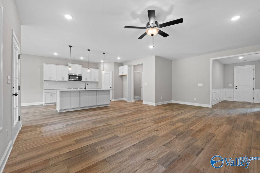 Open-concept kitchen and living area with white cabinets, hardwood floors, ceiling fan in Davidson Homes Montgomery B, Hartselle, AL