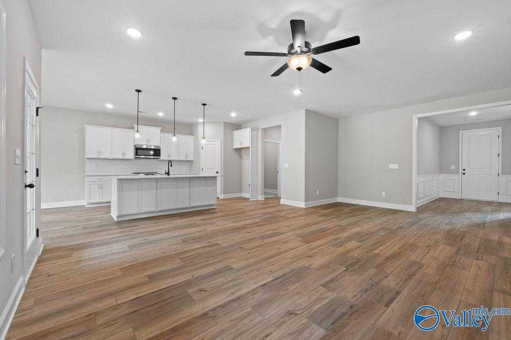 Open-concept kitchen and living area with white cabinets, hardwood floors, ceiling fan in Davidson Homes Montgomery B, Hartselle, AL