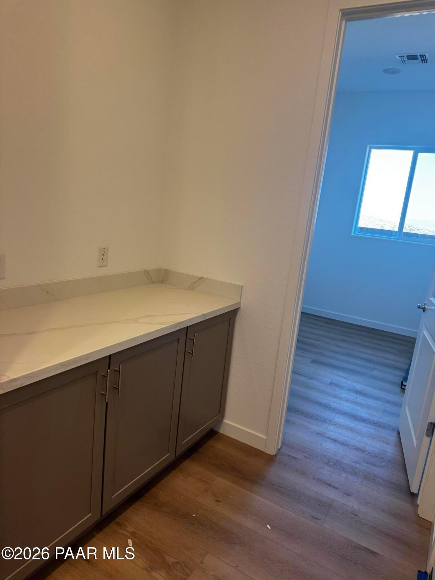 Modern laundry room featuring quartz countertop, gray cabinets, and open doorway in Davidson Homes The Blaze C, Prescott, Arizona