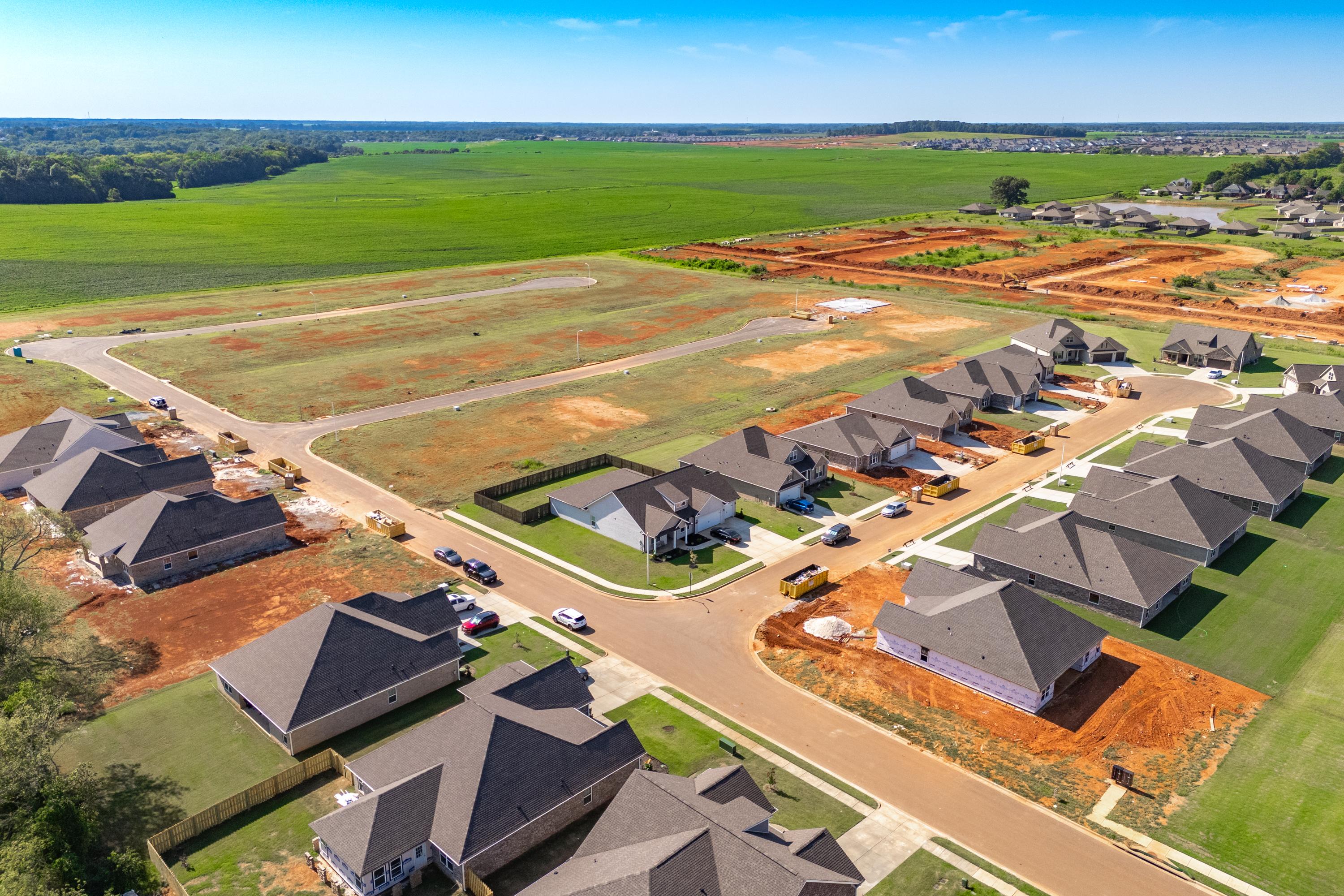 Aerial view of new homes under construction at Pikes Ridge in Meridianville, Alabama amid green fields and red clay lots
