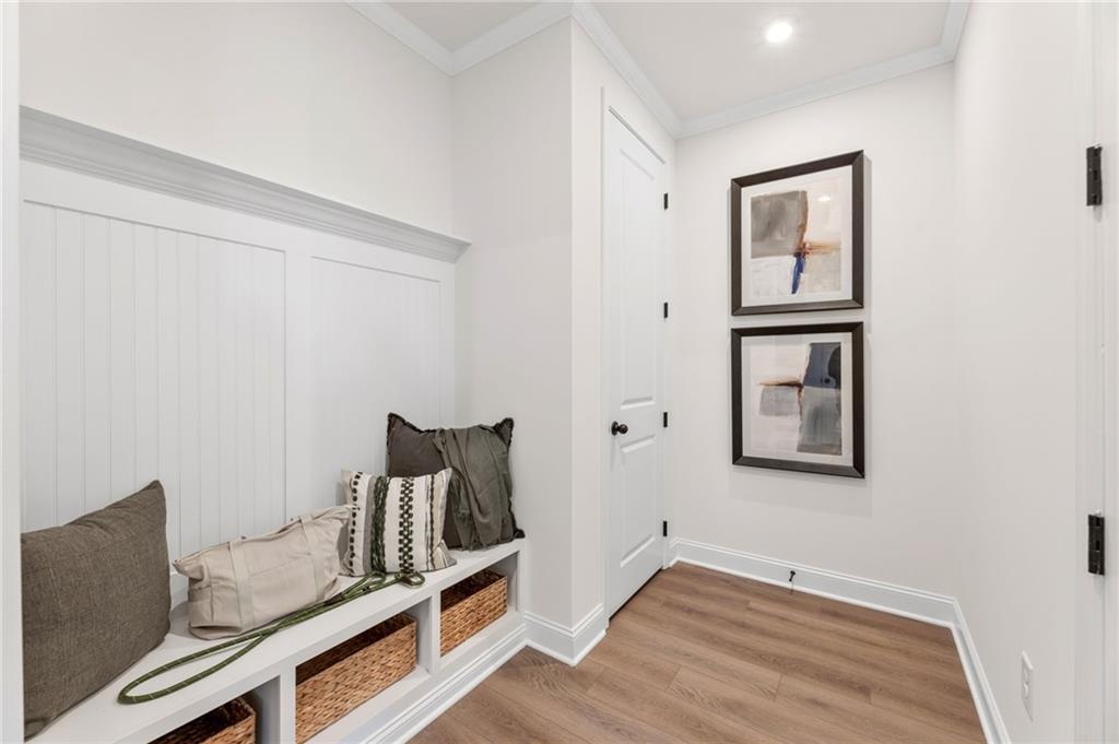 Inviting built-in mudroom bench with gray cushions, pillows, and wicker baskets in Davidson Homes The Aspen A, Buford, Georgia
