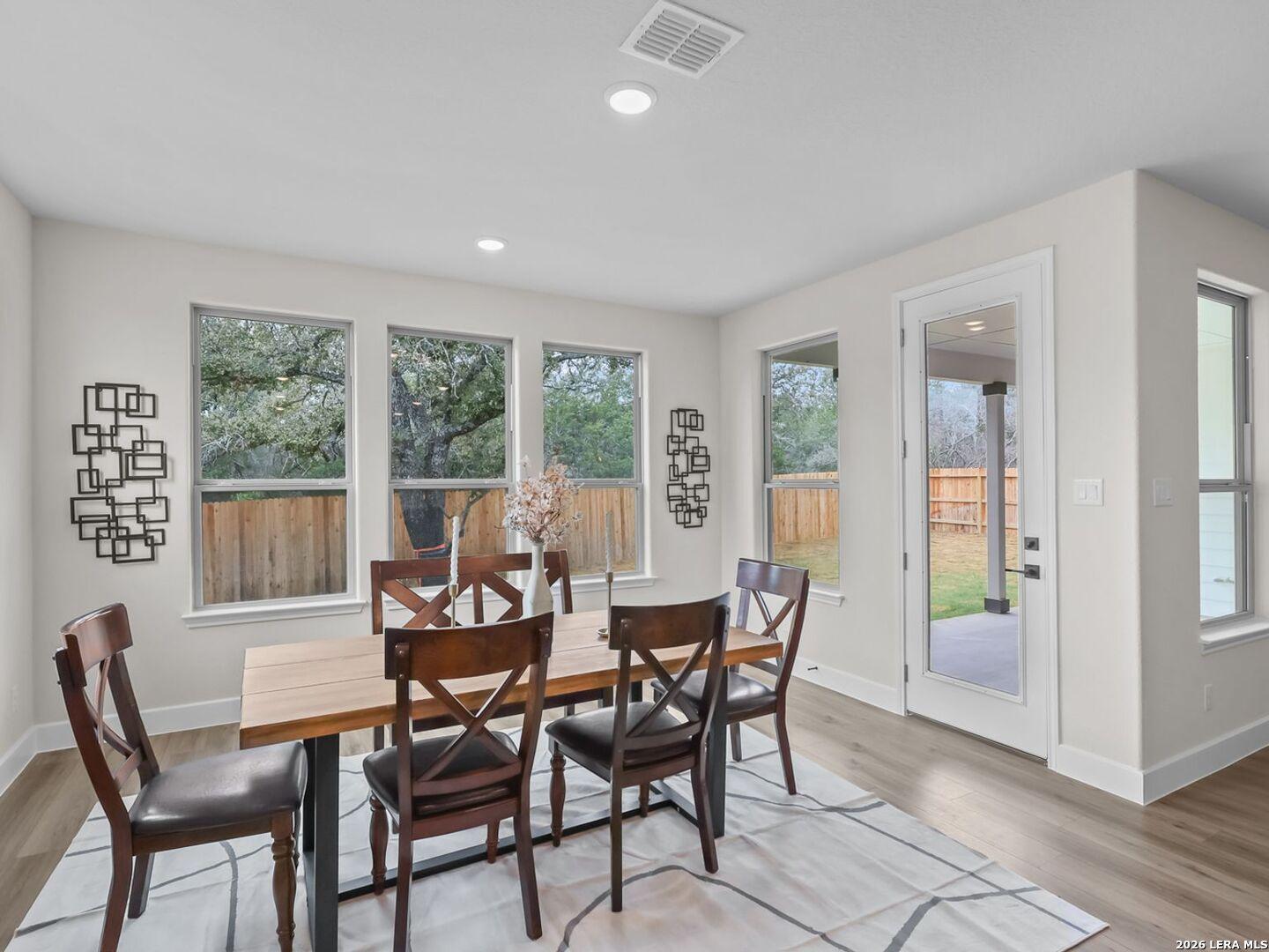 Bright dining area with wood table and patio access in The Belmont H floor plan at Potranco Oaks, Castroville, Texas.