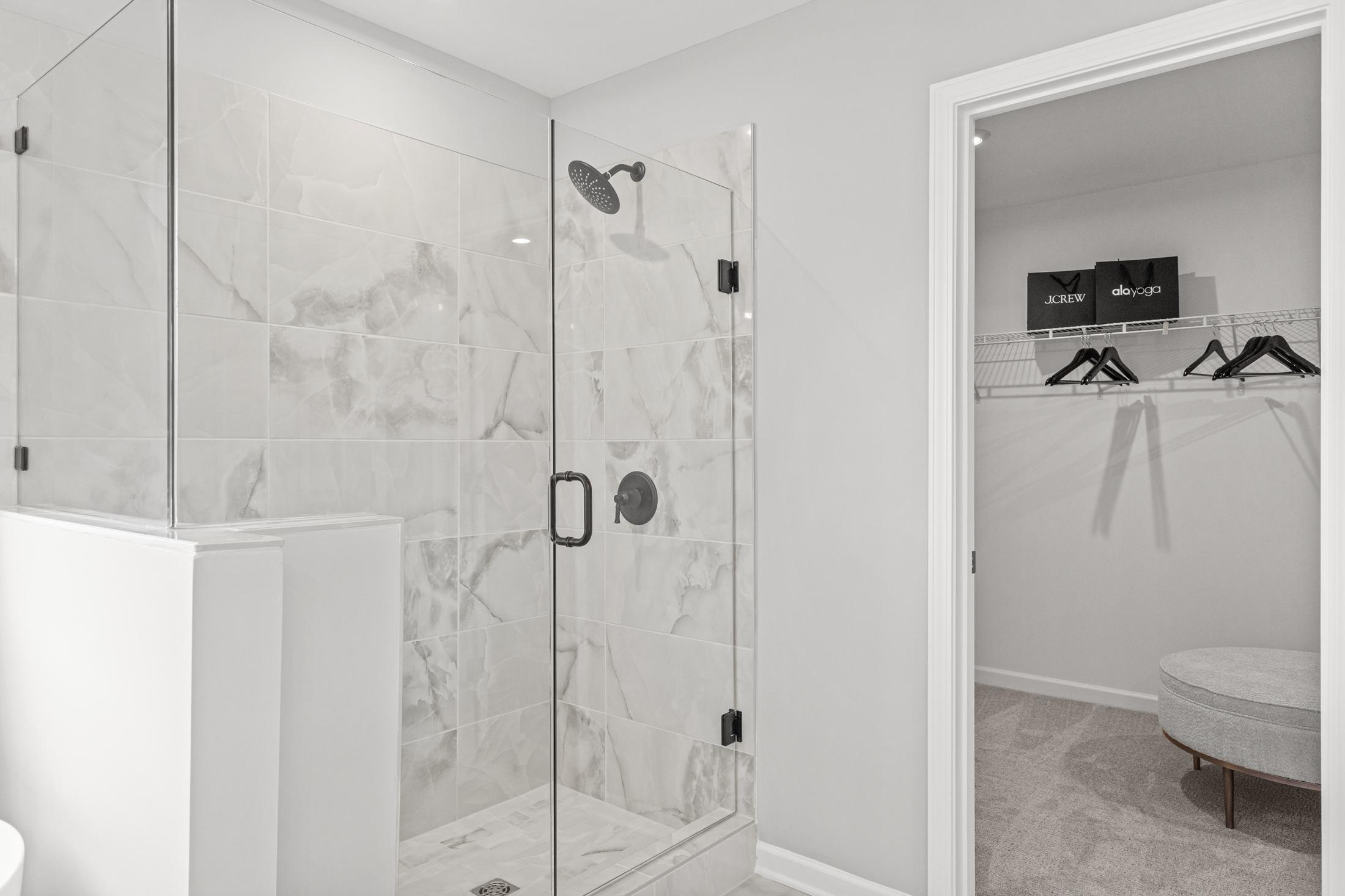 Master bathroom in The Hickory B with frameless glass walk-in shower, subway tile, and adjacent walk-in closet