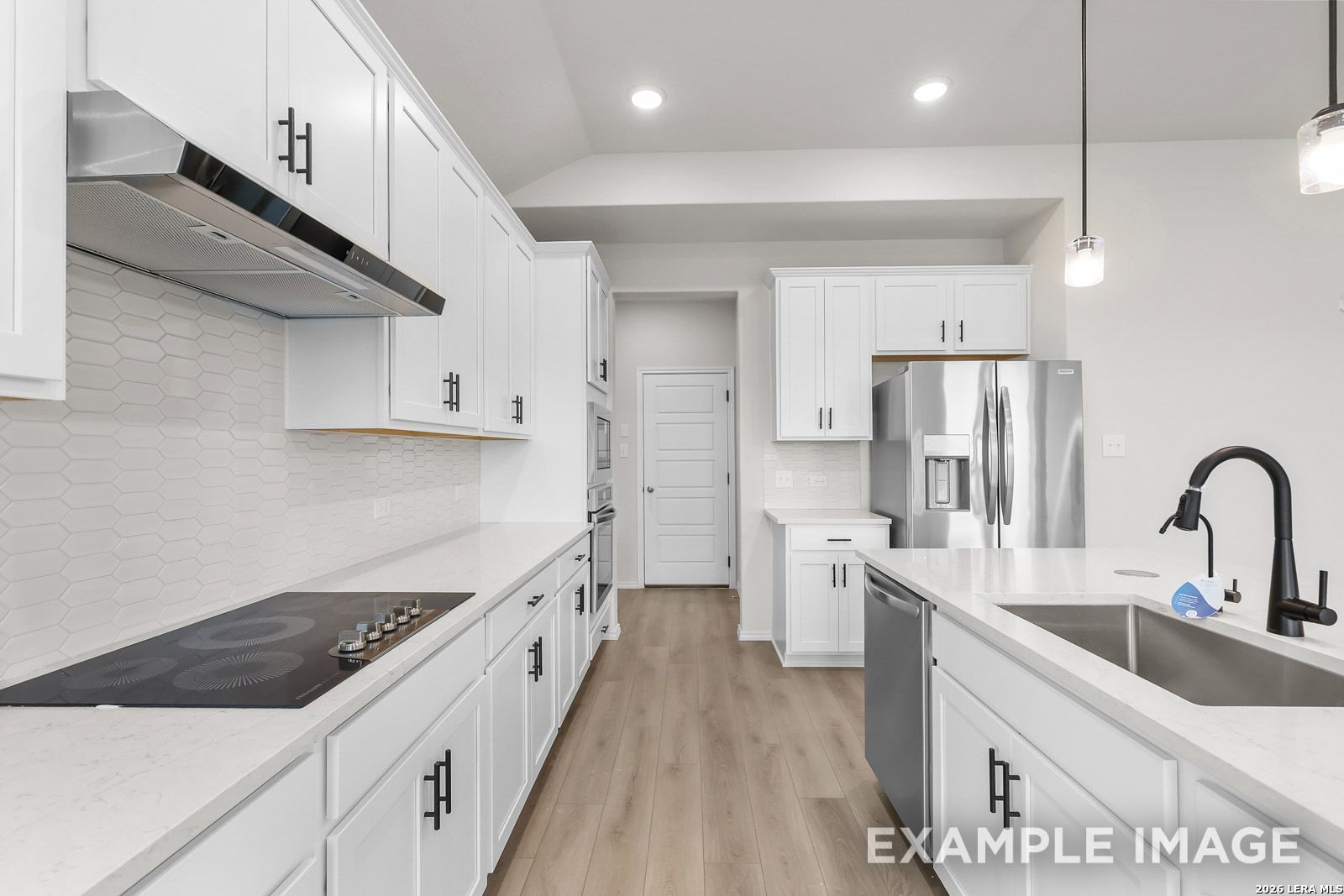 Modern white kitchen with stainless steel appliances and quartz countertops in Davidson Homes The Sequoia C, San Antonio.