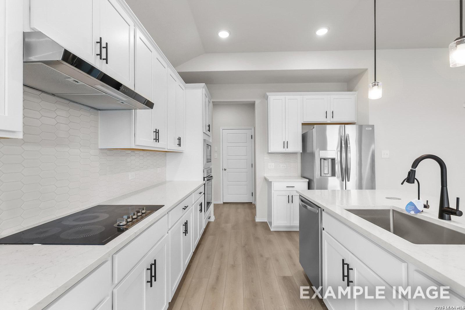 Modern white kitchen with stainless steel appliances and quartz countertops in Davidson Homes The Sequoia C, San Antonio.