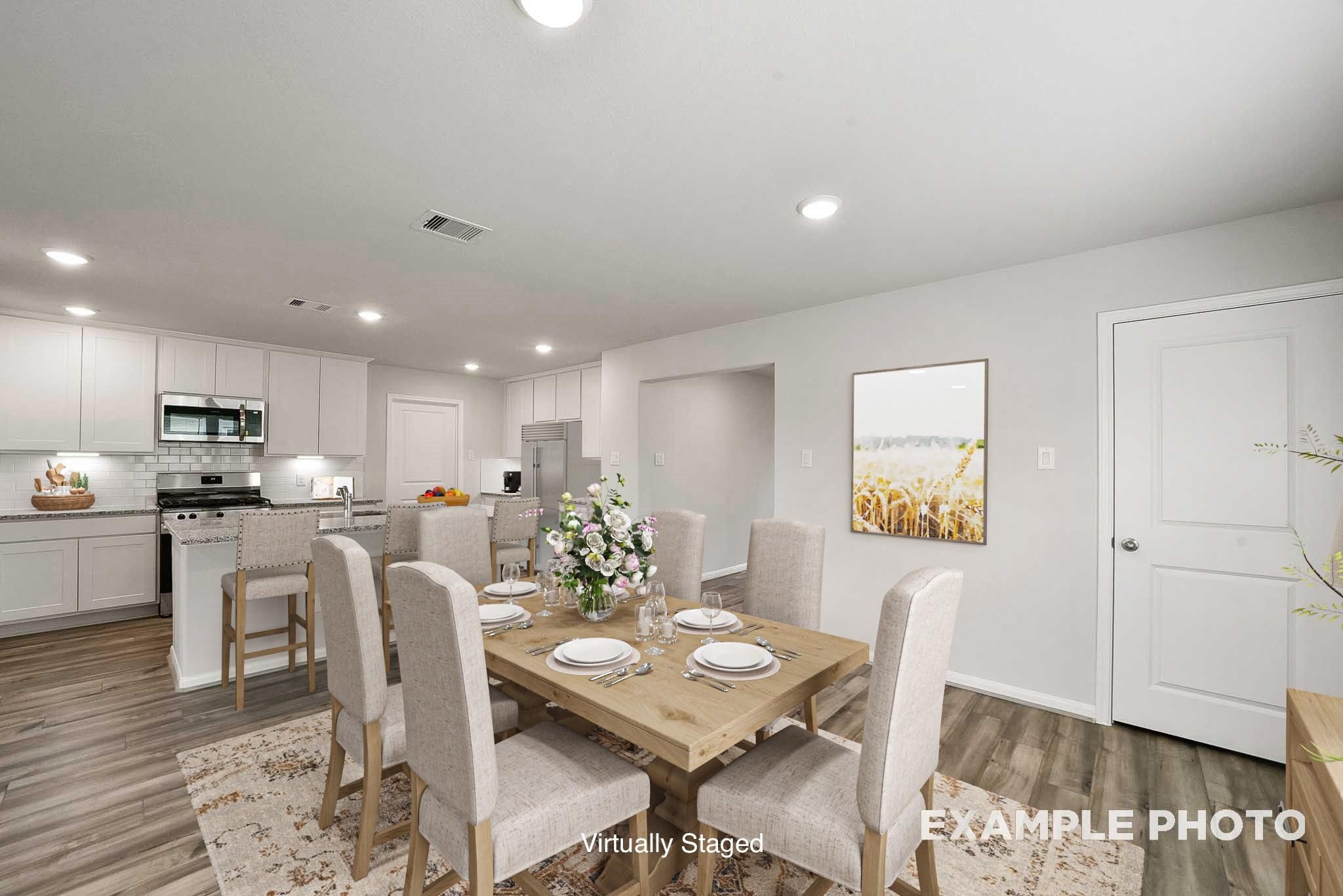 Bright open-concept dining area with wooden table, beige chairs, and adjacent white kitchen in Davidson Homes Tierra B, Beasley, Texas