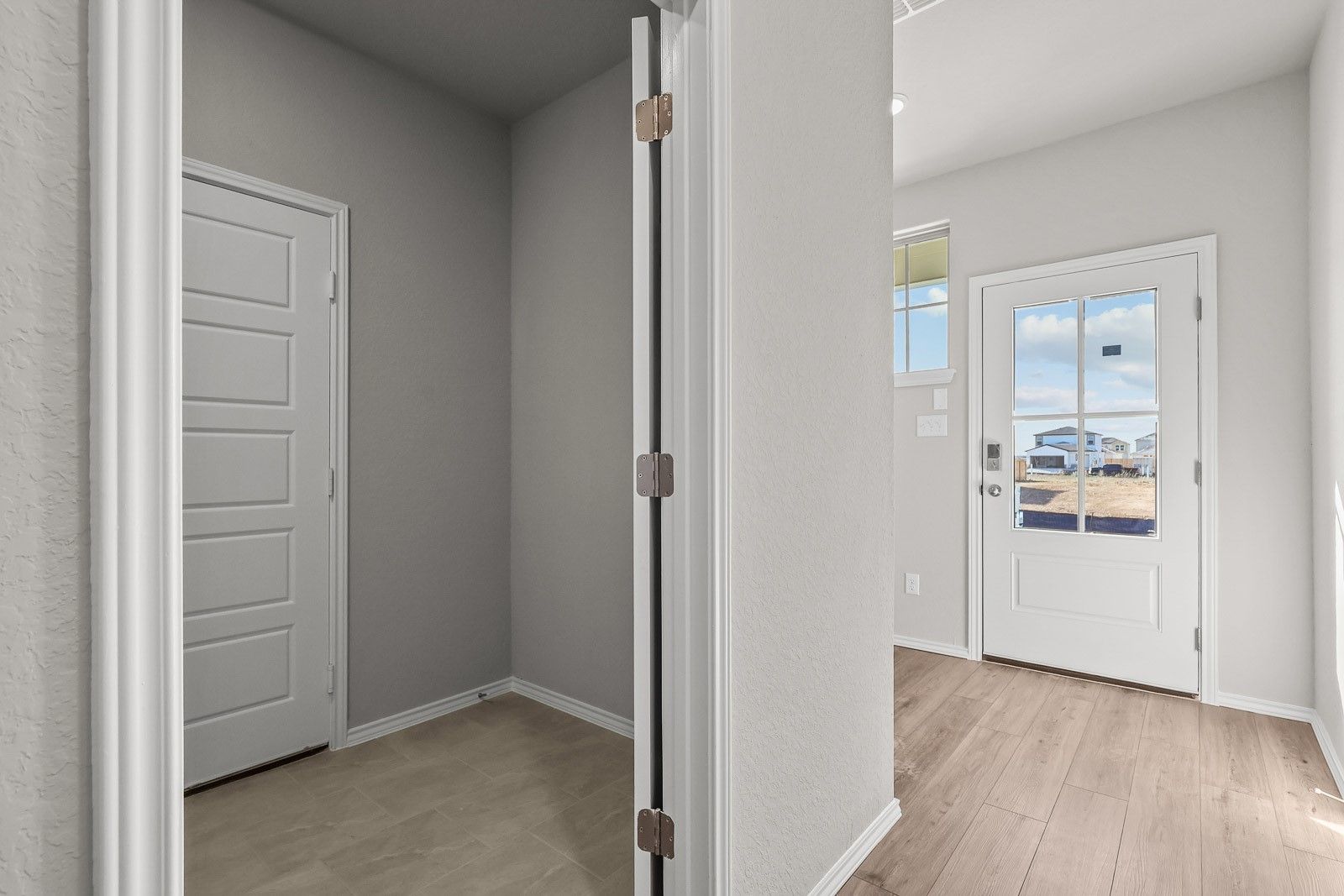 Mudroom entry area with tile flooring and glass-paneled front door in The Frio G plan by Davidson Homes in Heartland, TX.