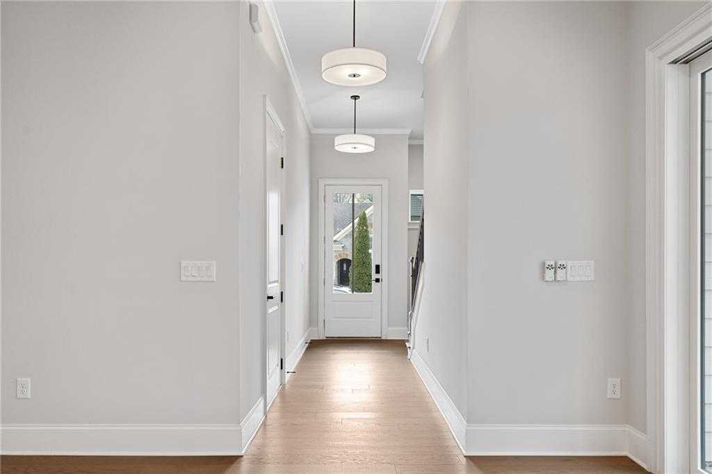 Elegant hallway with light gray walls, hardwood floors, pendant lights, and glass back door in Davidson Homes The Seaside B, Woodstock, Georgia