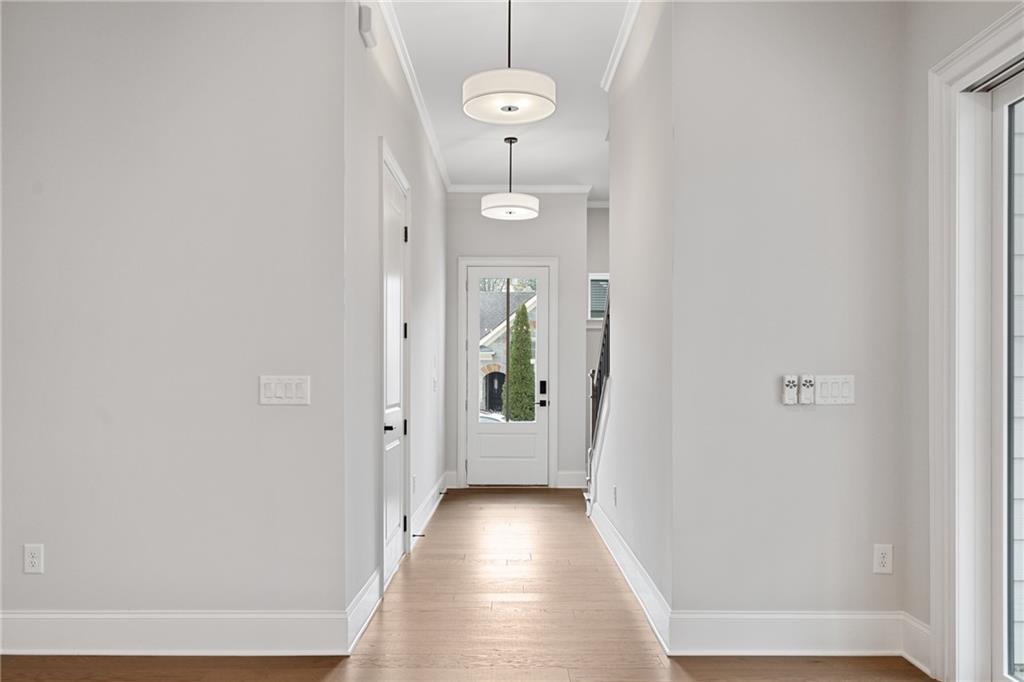 Elegant hallway with light gray walls, hardwood floors, pendant lights, and glass back door in Davidson Homes The Seaside B, Woodstock, Georgia
