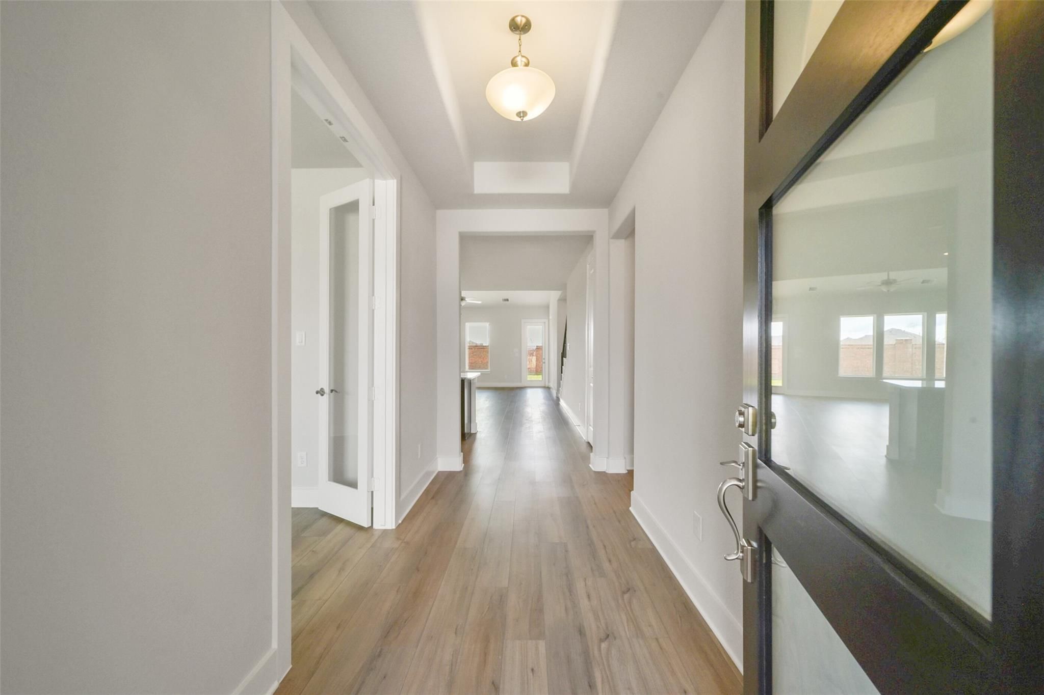 Spacious hallway with hardwood floors, white walls, and frosted glass door in Davidson Homes The Zion A, Lago Mar, Texas City