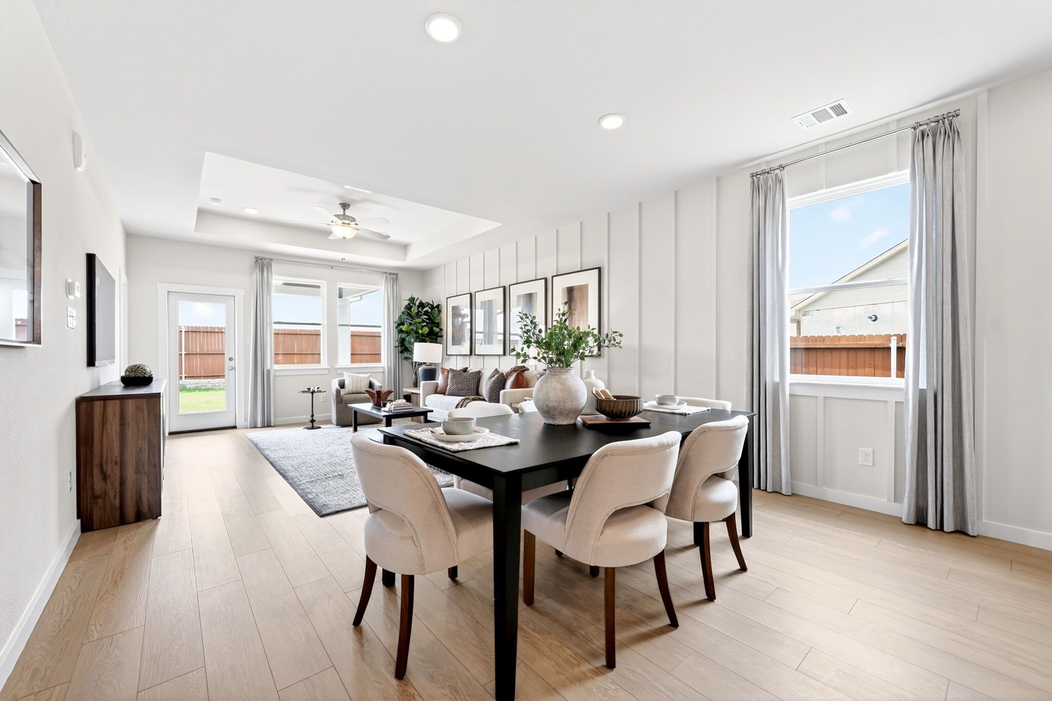 Open-concept dining room in Heartland Texas by Davidson Homes with black table, cream chairs, light oak floors, shiplap walls