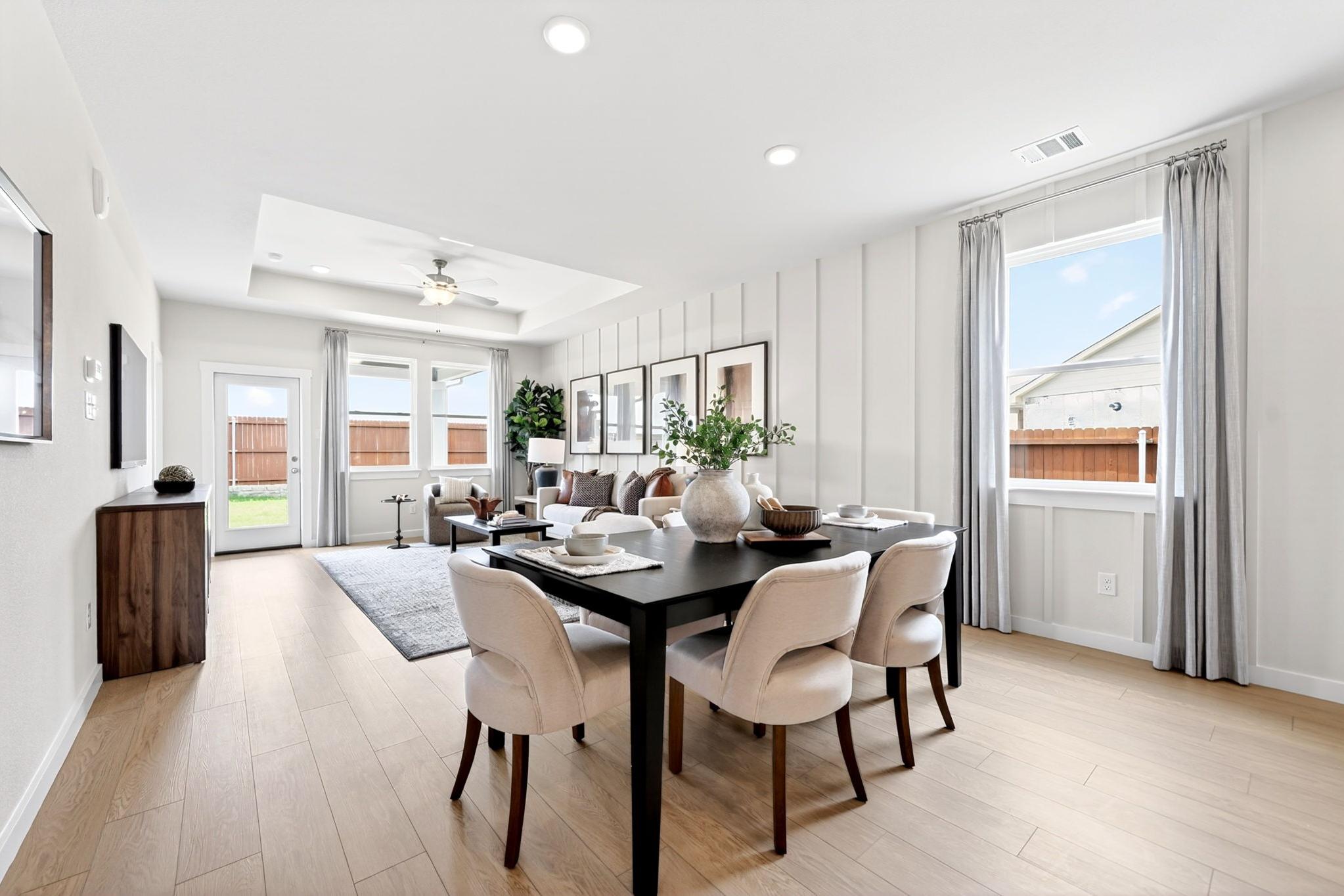 Open-concept dining room in Heartland Texas by Davidson Homes with black table, cream chairs, light oak floors, shiplap walls