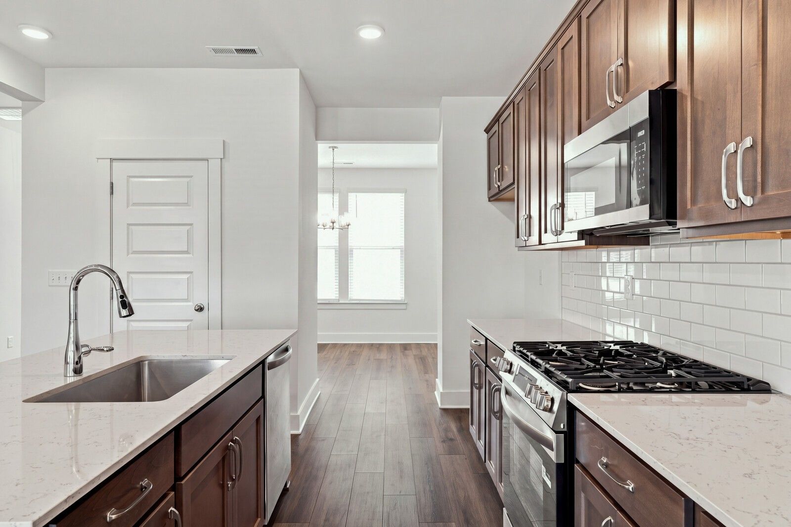 Modern kitchen with dark wood cabinets, quartz countertops, gas range, and subway tile backsplash in Davidson Homes Willow C plan