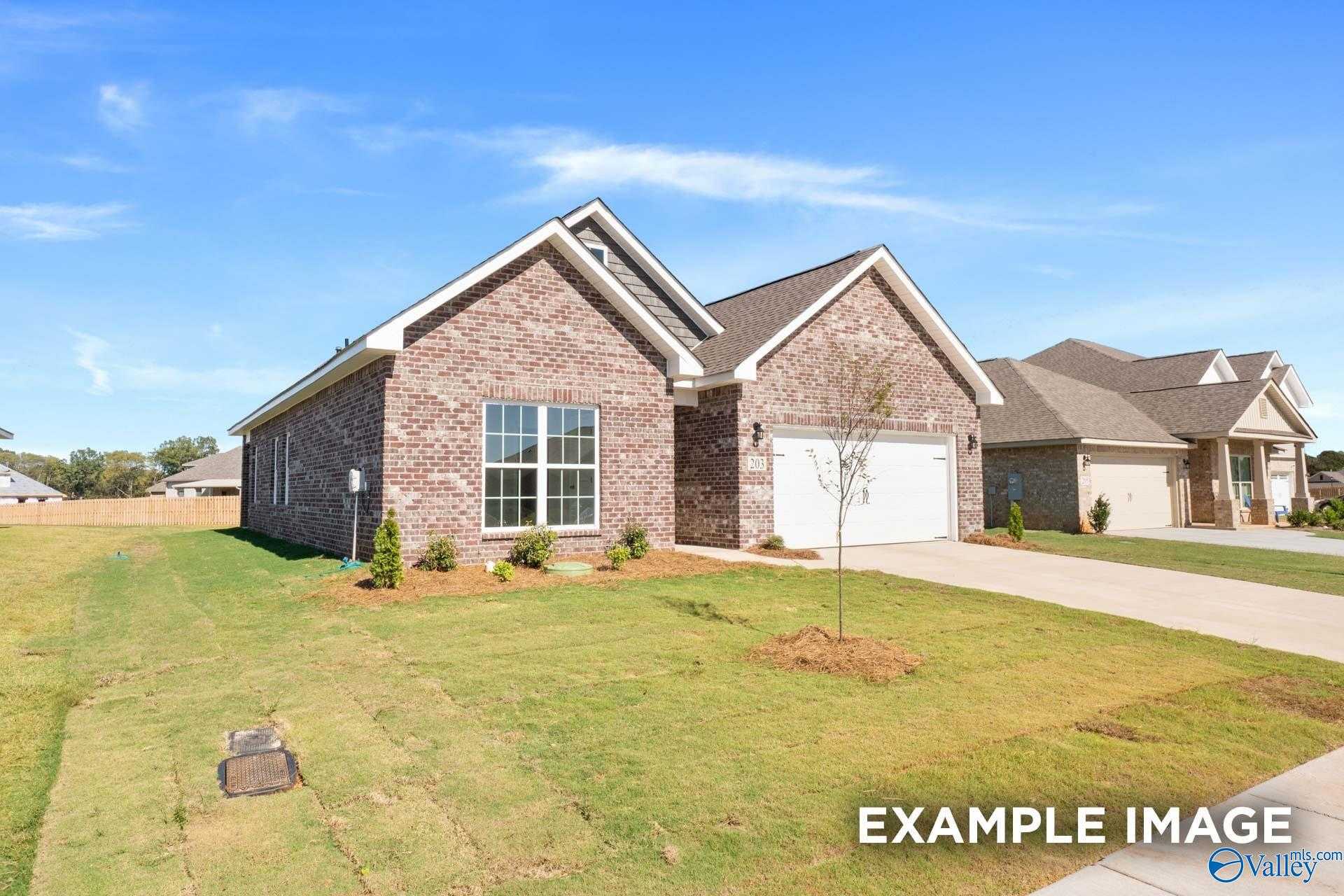 Brick single-story home with 2-car garage, fresh sod yard, and young trees under blue sky in Walker's Hill, Meridianville, Alabama