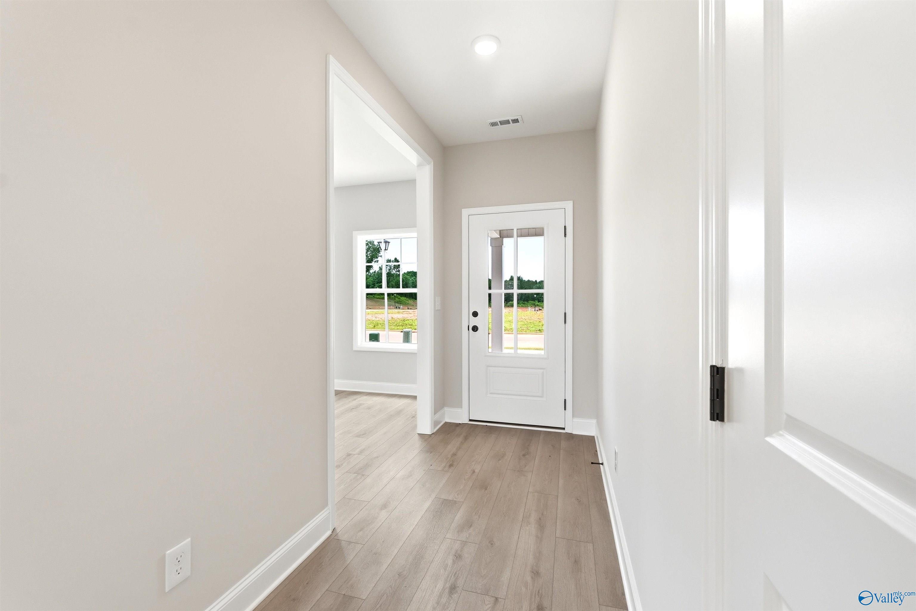 Bright foyer entry with wood-style flooring in The Shelby A floor plan at Wood Trail in Toney, Alabama.