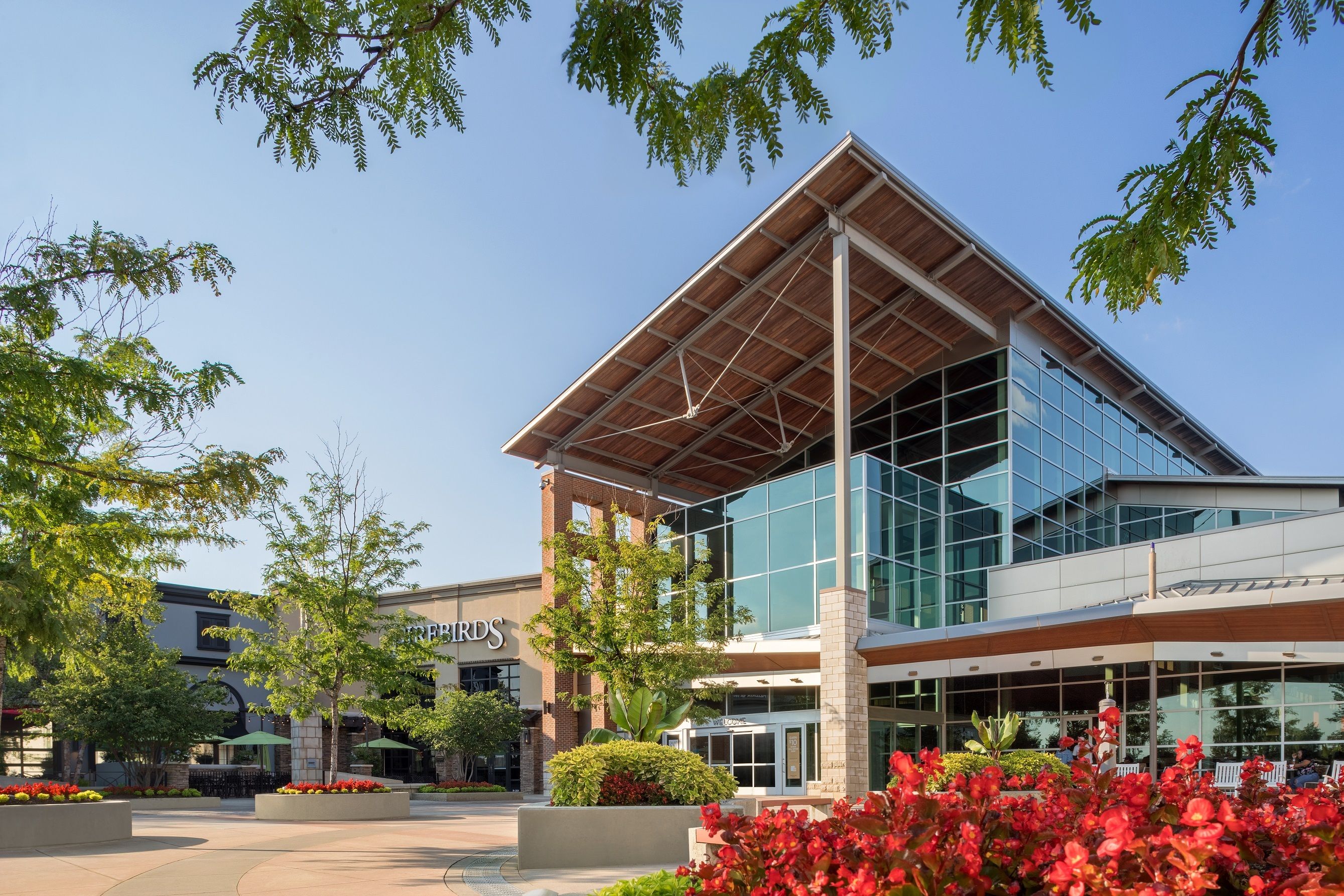 Modern shopping center near Long Creek Townhomes in Charlotte, NC featuring glass architecture and landscaped flower beds.