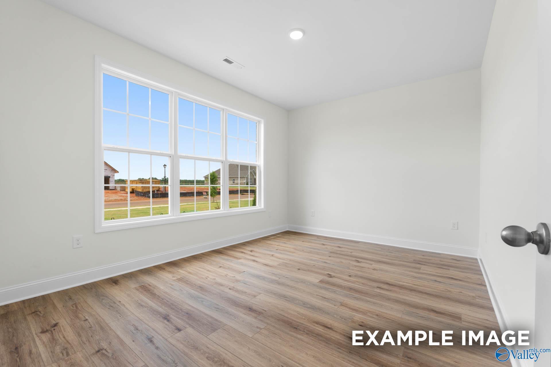 Bright empty bedroom with large windows overlooking grassy yard in Davidson Homes The Oxford, Huntsville, Alabama
