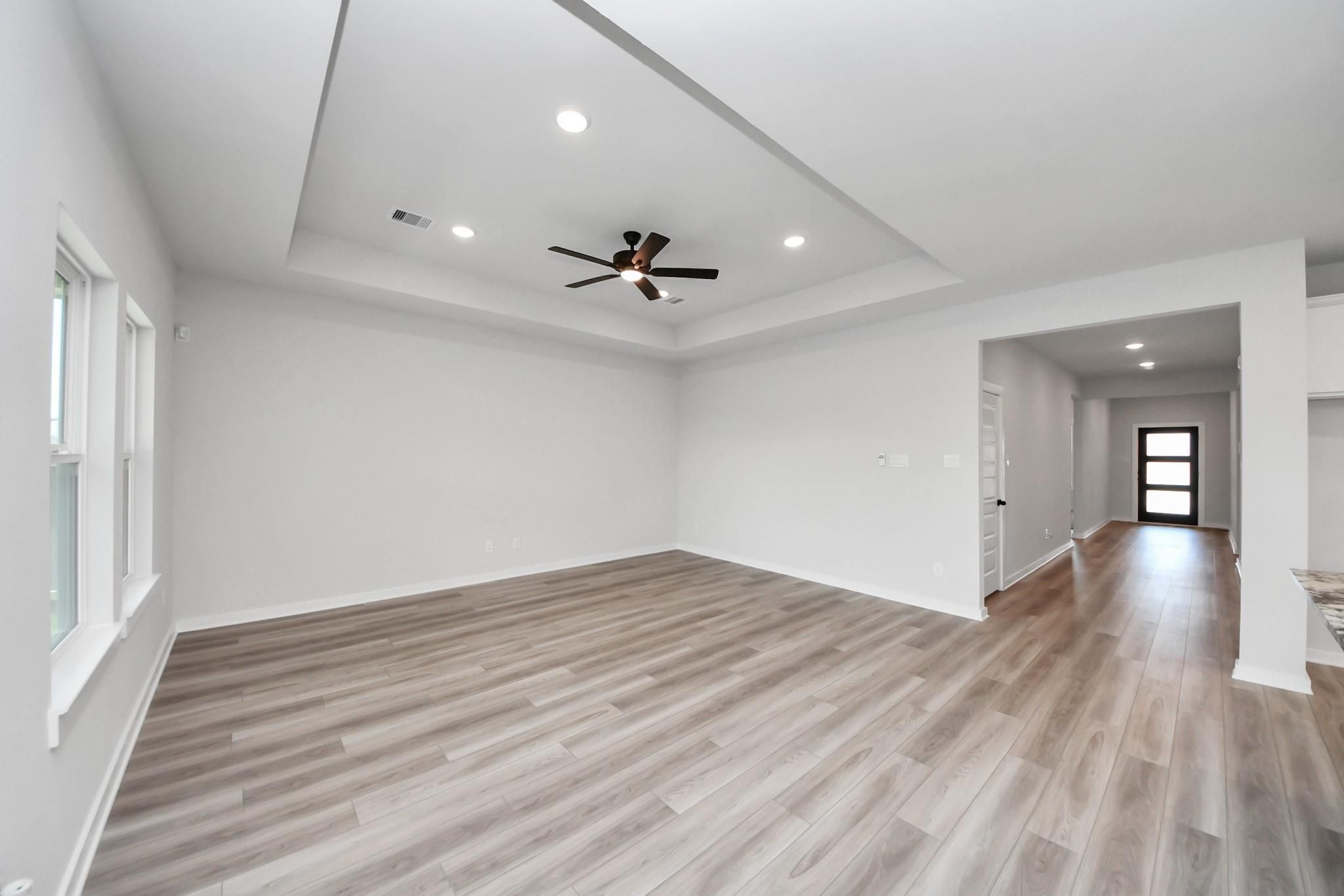Spacious living room with tray ceiling and wood-look flooring in The Everett C floor plan at River Ranch Meadows, Dayton.