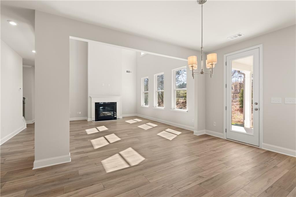 Bright family room with gas fireplace, hardwood floors, large windows, and French doors in Davidson Homes Danbury C, Buford, GA