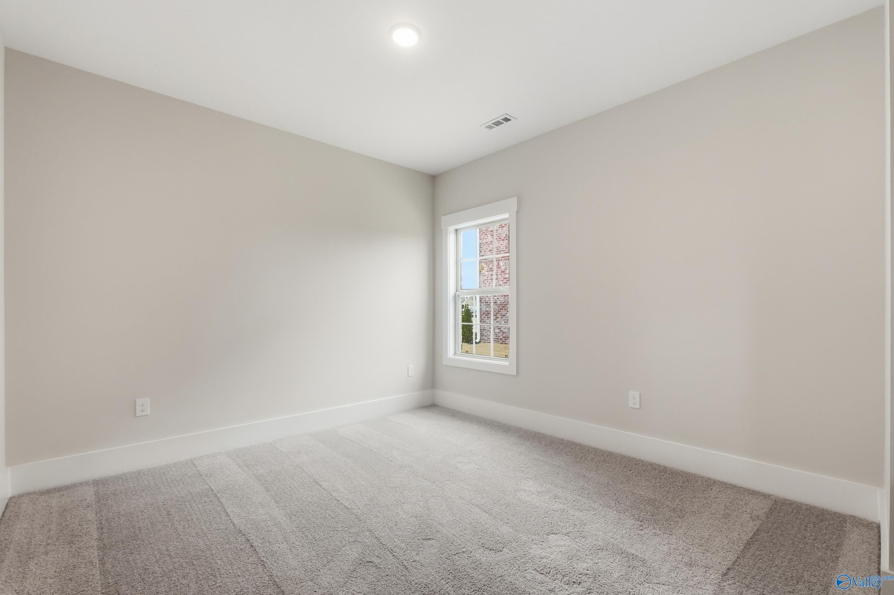 Empty bedroom featuring light gray walls, large window with blinds, and plush carpet in Davidson Homes The Finleigh, Meridianville, Alabama