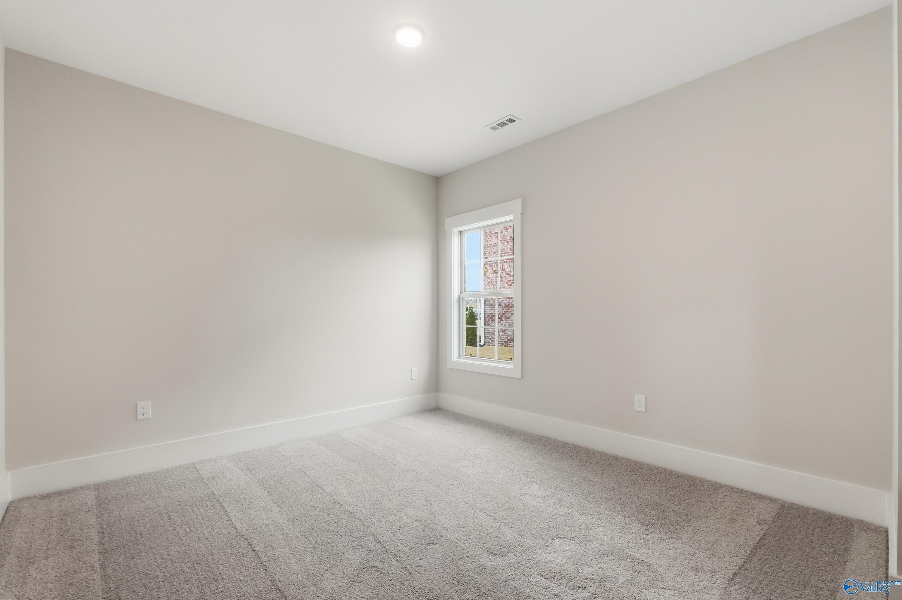 Empty bedroom featuring light gray walls, large window with blinds, and plush carpet in Davidson Homes The Finleigh, Meridianville, Alabama