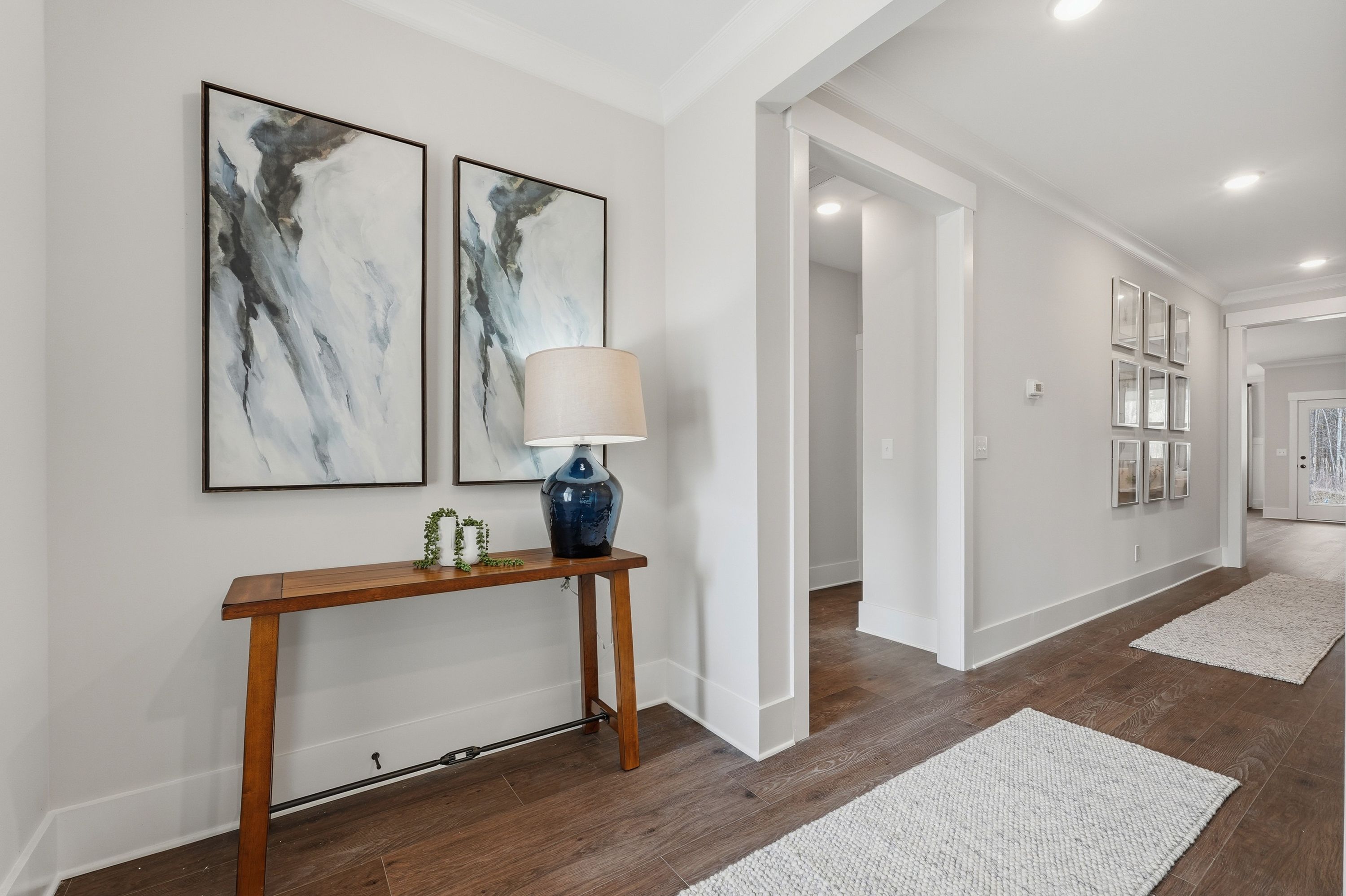 Elegant entryway hallway at Noble Ridge in Cullman Alabama with wooden console table blue lamp abstract art and hardwood floors