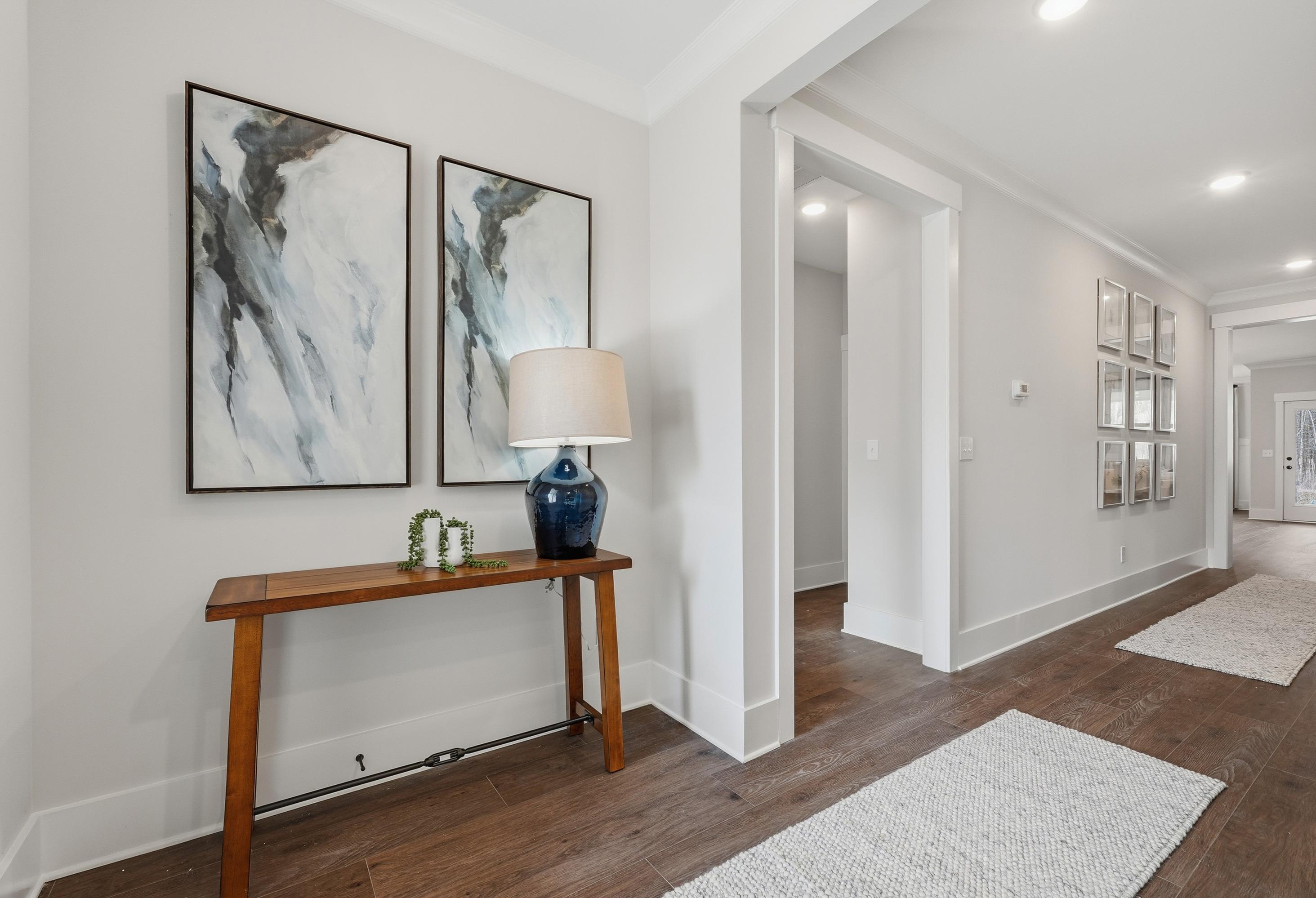 Bright hallway in The Hibiscus home design featuring modern wall art, wood console table, and hardwood flooring.