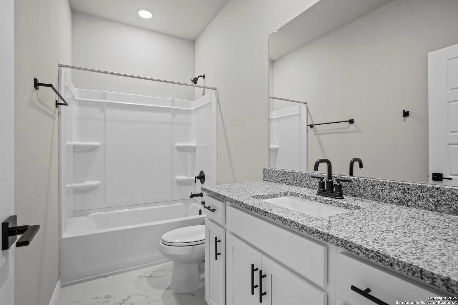 Bright secondary bathroom with granite vanity, tub-shower combo, white cabinets in Davidson Homes The Asheville E, Converse Texas