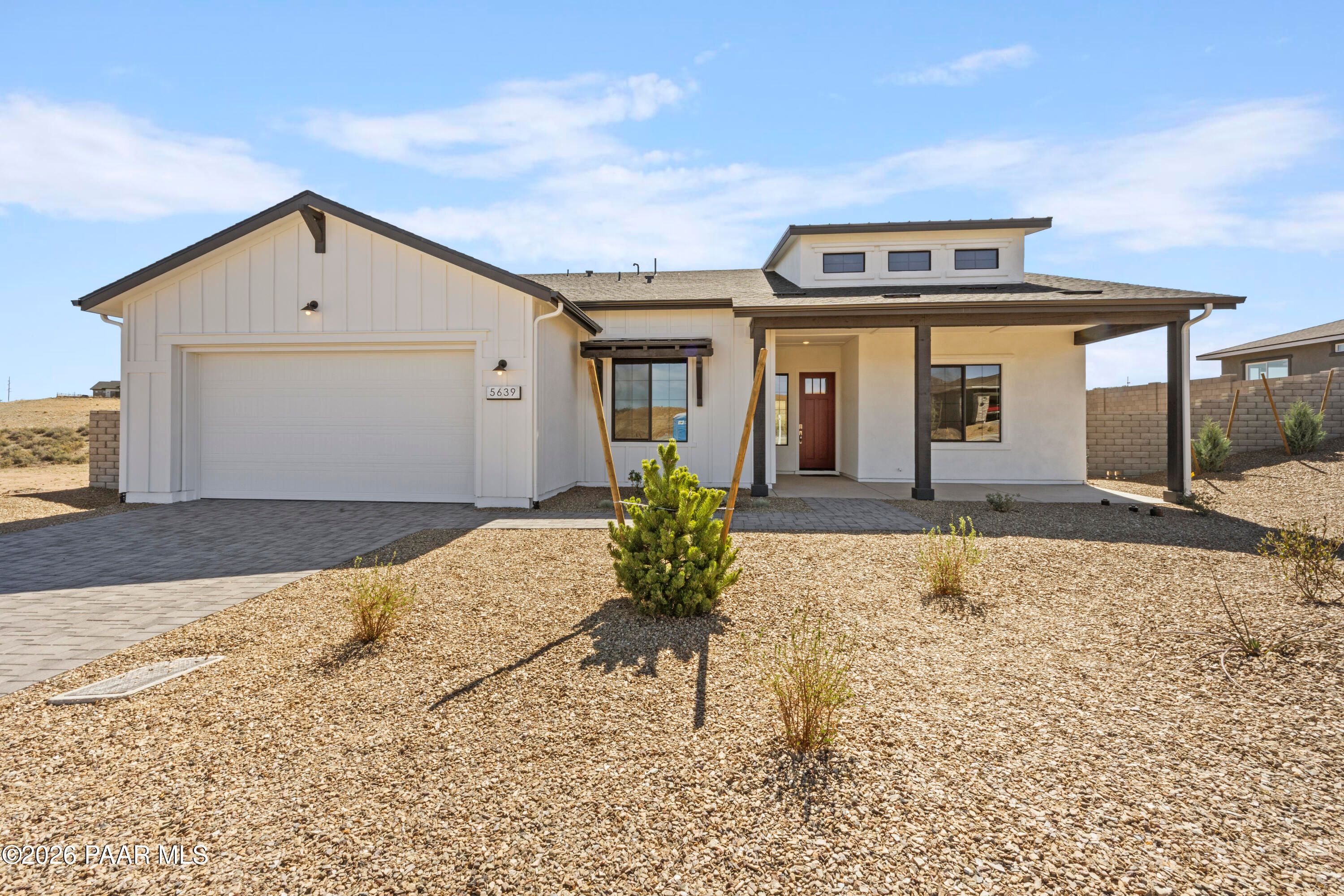 Modern white 1-story Davidson Homes Soleil E with 3-car garage, red door, and desert gravel yard in Hidden Hills, Prescott, AZ