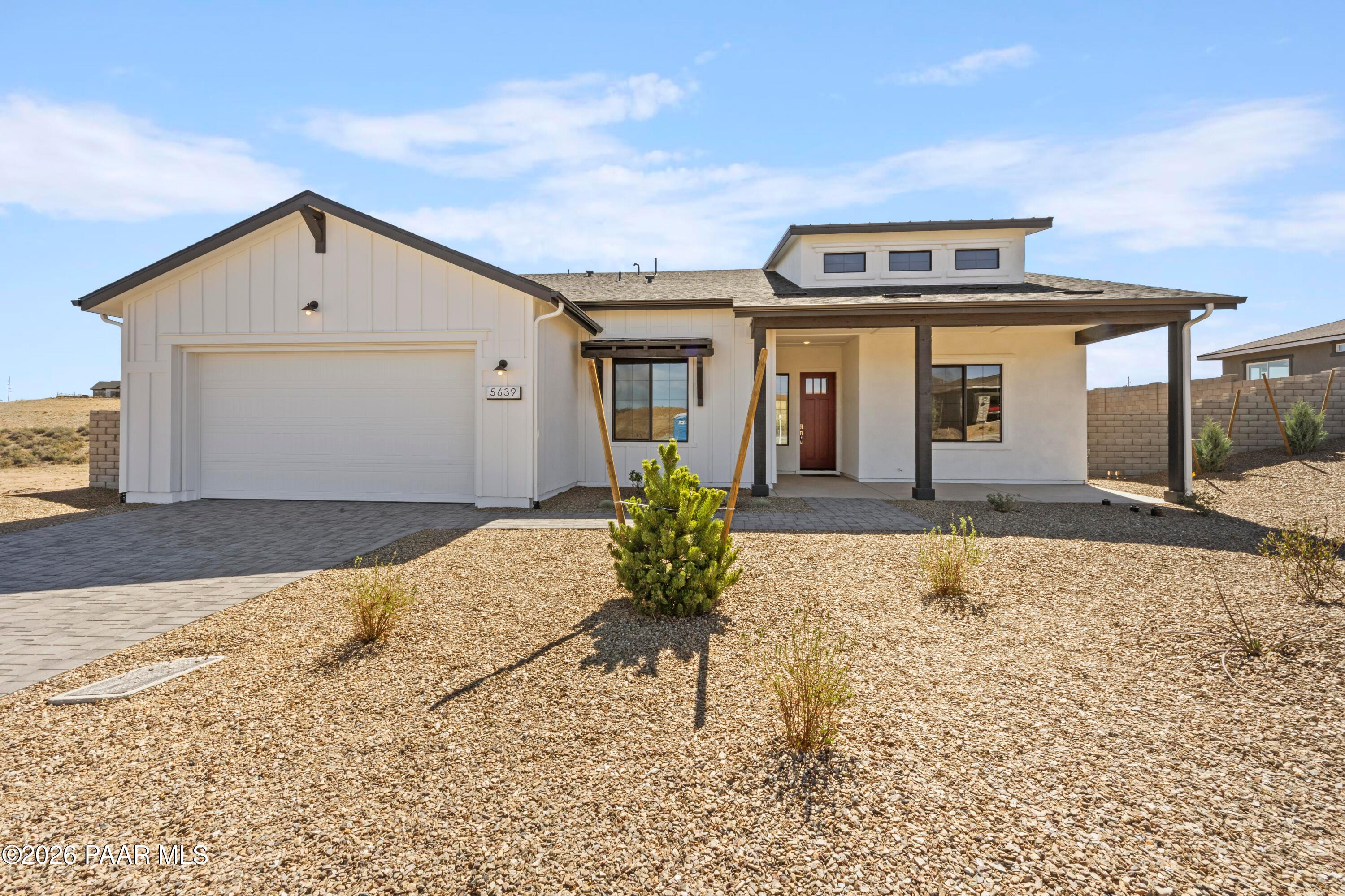 Modern white 1-story Davidson Homes Soleil E with 3-car garage, red door, and desert gravel yard in Hidden Hills, Prescott, AZ