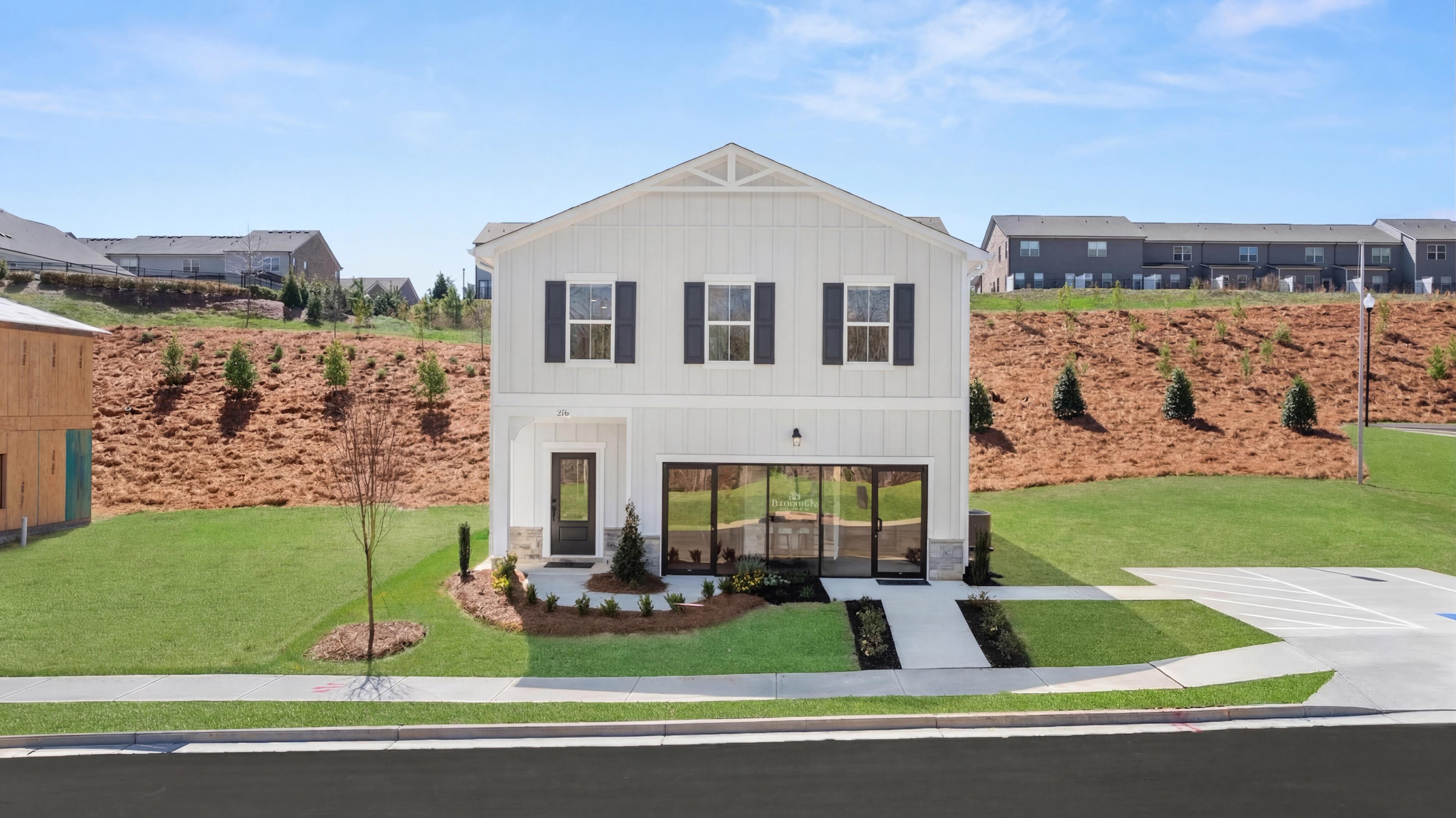 White two-story craftsman home with gabled roof, black shutters, glass porch, and landscaped yard in The Bluffs, Canton, Georgia