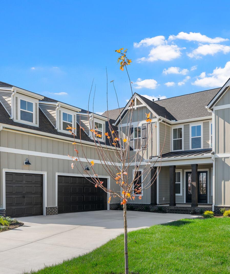 Modern white brick two-story home at Shelton Square in Murfreesboro TN with covered porch, balcony, and two-car garage