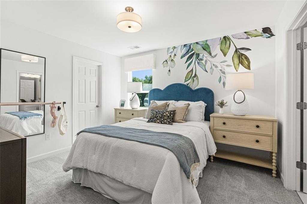 Cozy bedroom with blue tufted headboard bed, botanical leaf wallpaper accent wall, oak nightstands, and carpeted floor in Hoschton, Georgia home