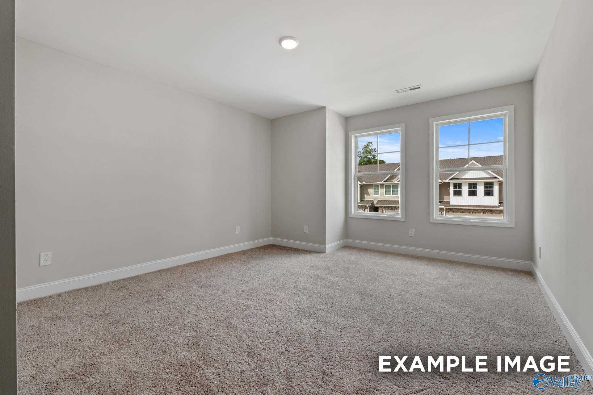 Bright secondary bedroom with large windows, gray walls, and carpet in The Camden by Davidson Homes, Huntsville, Alabama