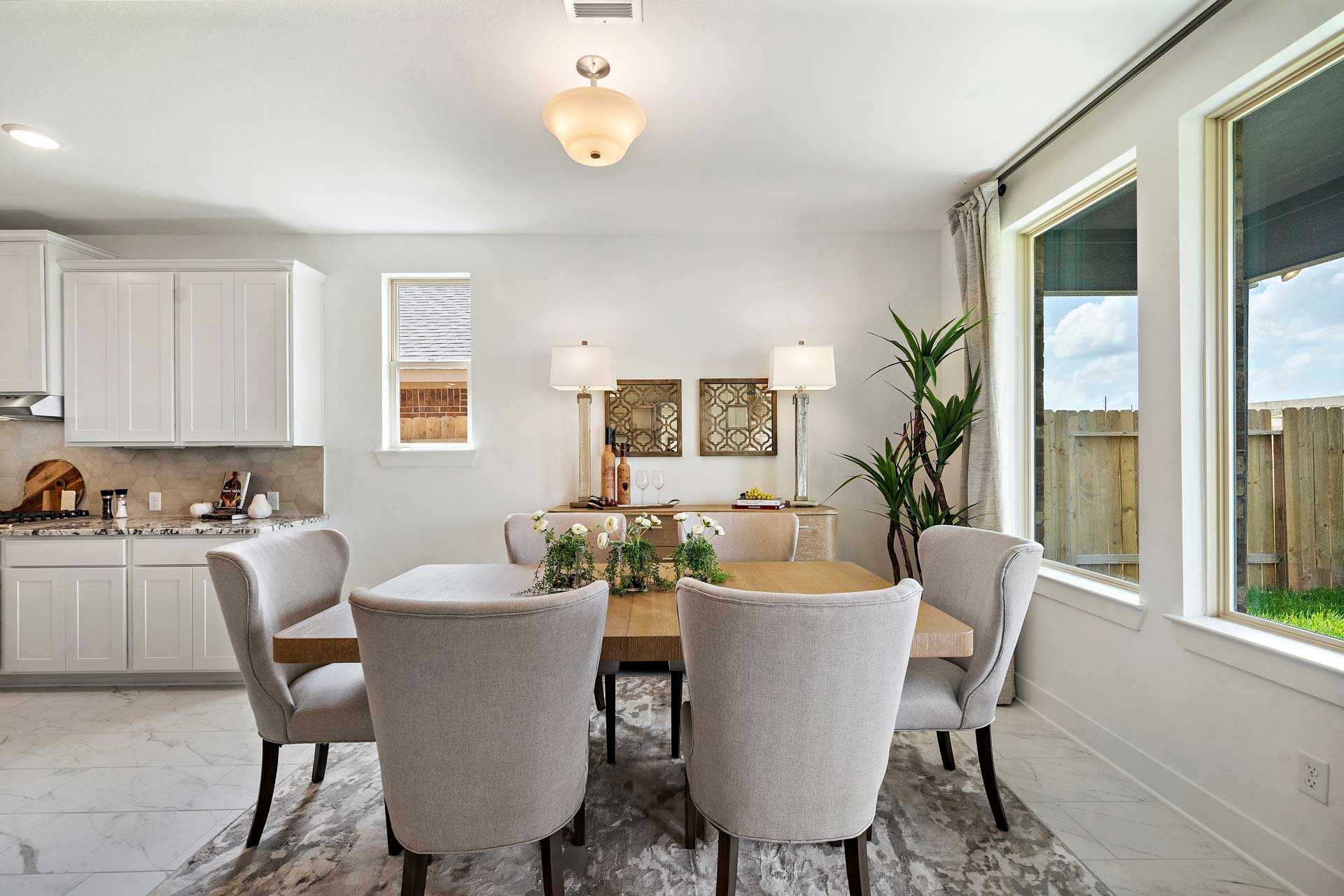 Elegant dining room at Sierra Vista in Rosharon TX featuring wooden table white chairs large windows and modern decor