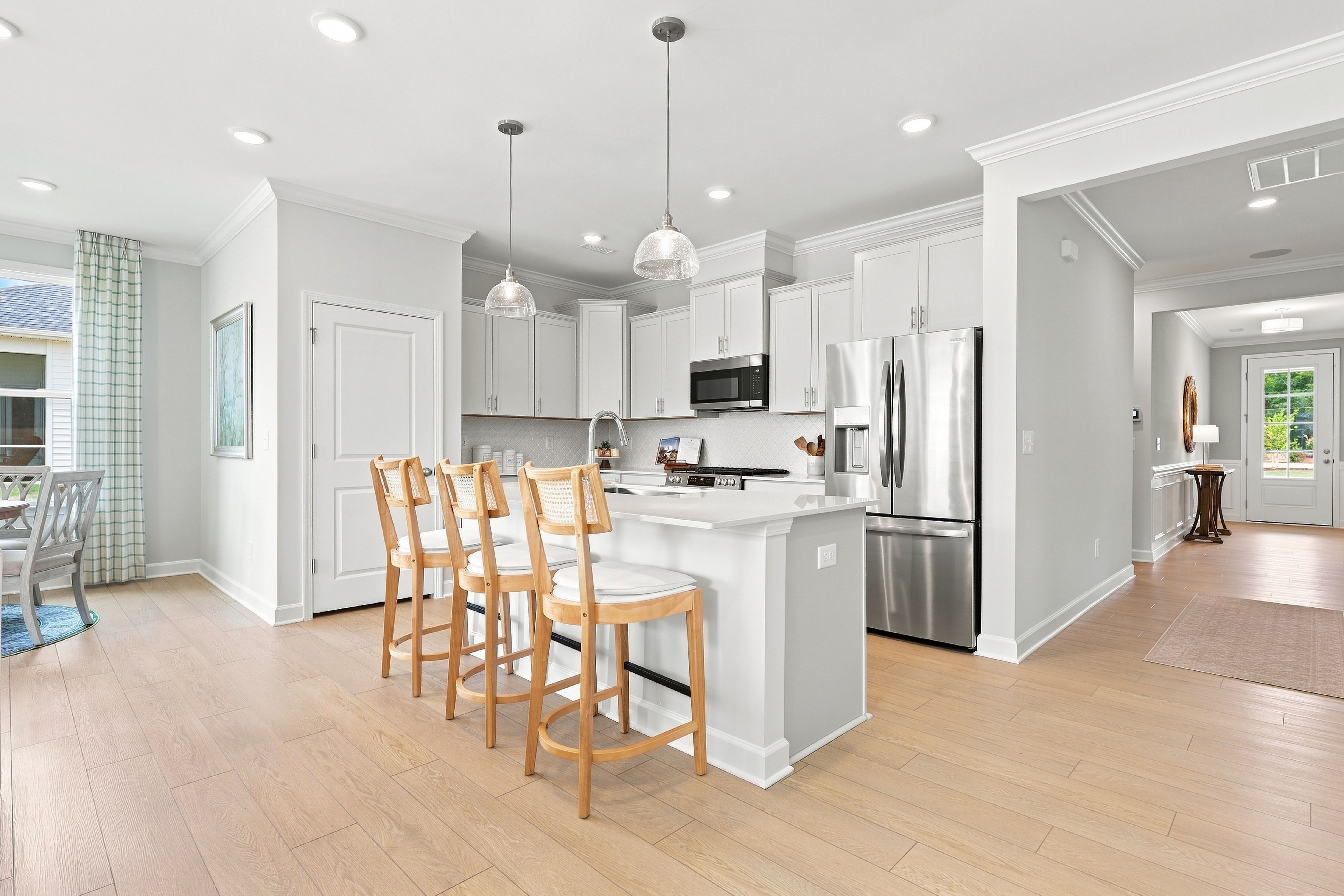 Modern kitchen in The Daphne C featuring white cabinetry, stainless steel appliances, and a central island with bar seating.