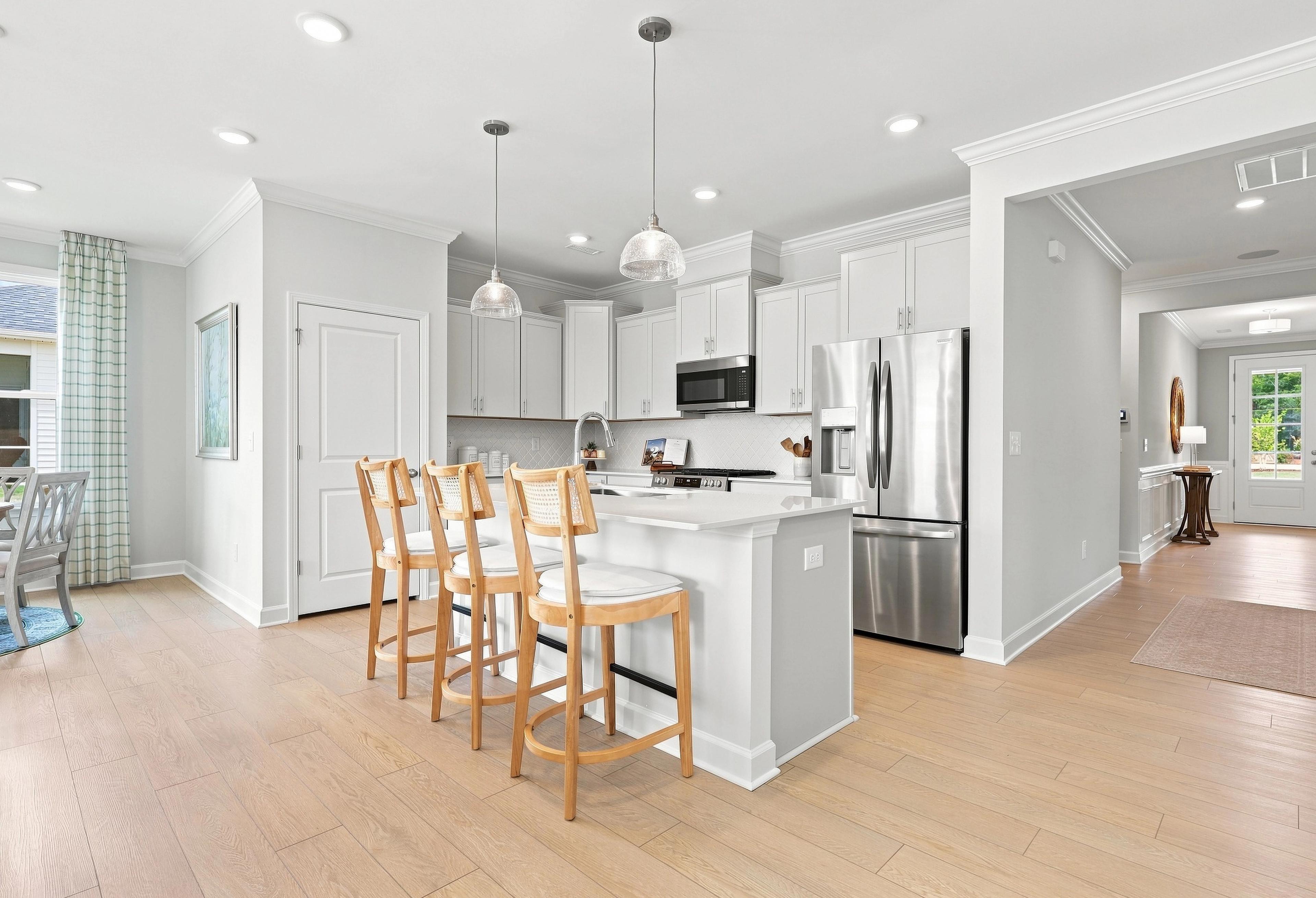 Modern kitchen in The Daphne C featuring white cabinetry, stainless steel appliances, and a central island with bar seating.