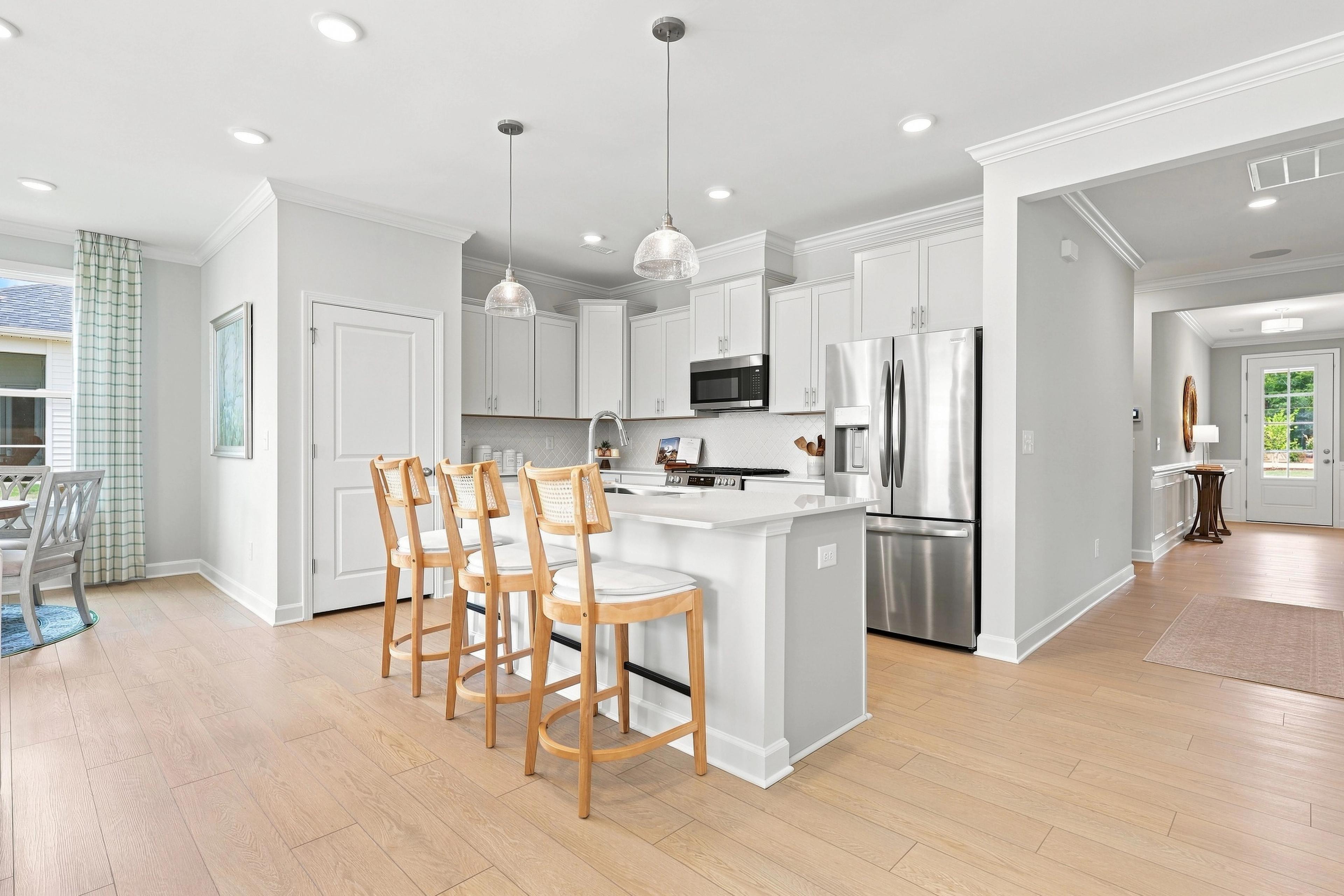 Modern kitchen in The Daphne D featuring white cabinetry, quartz island, stainless steel appliances, and open-concept design.