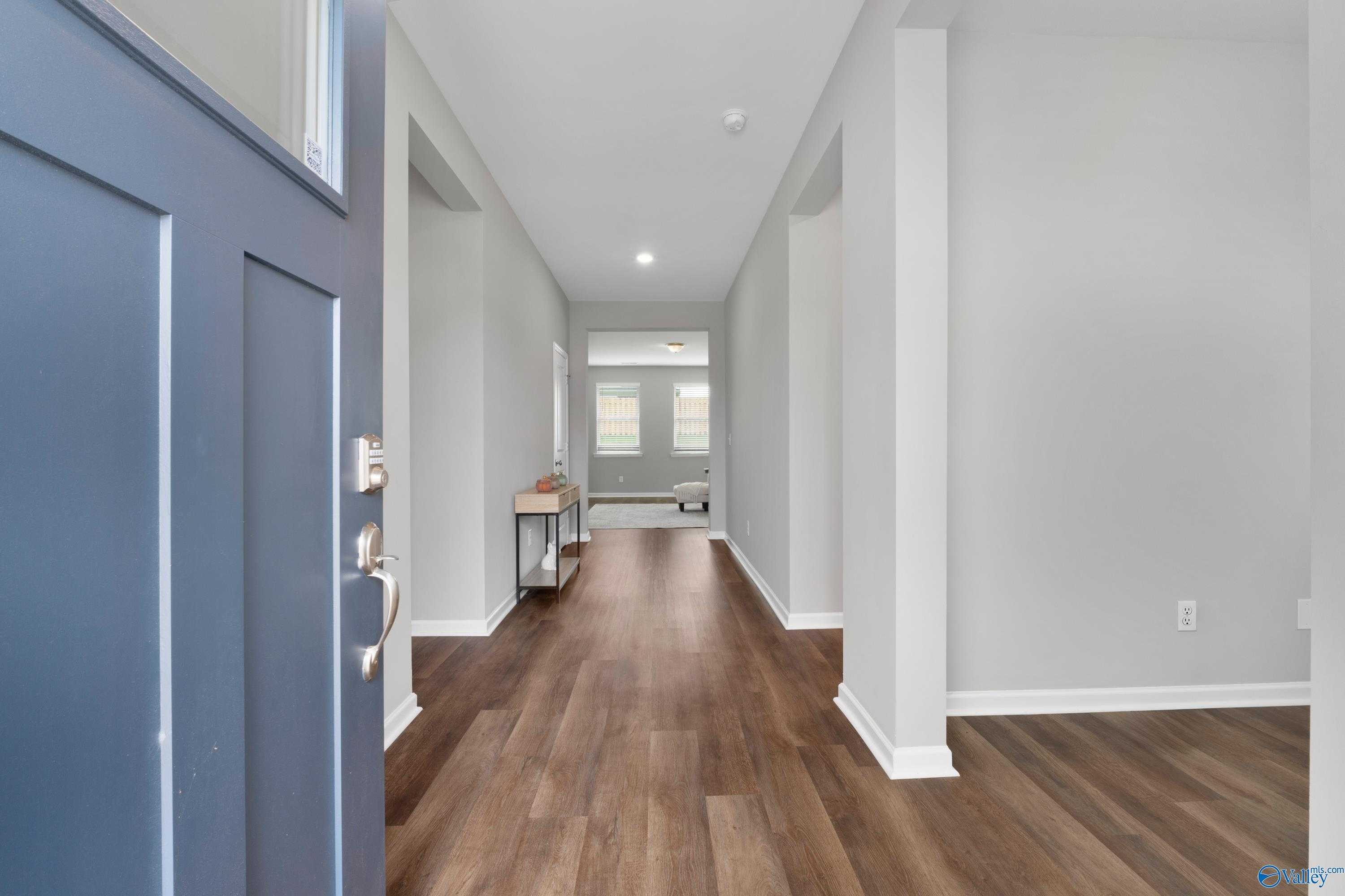 Welcoming foyer with navy blue front door, hardwood floors, and light gray walls in Evermore Homes The Noble, Madison Alabama